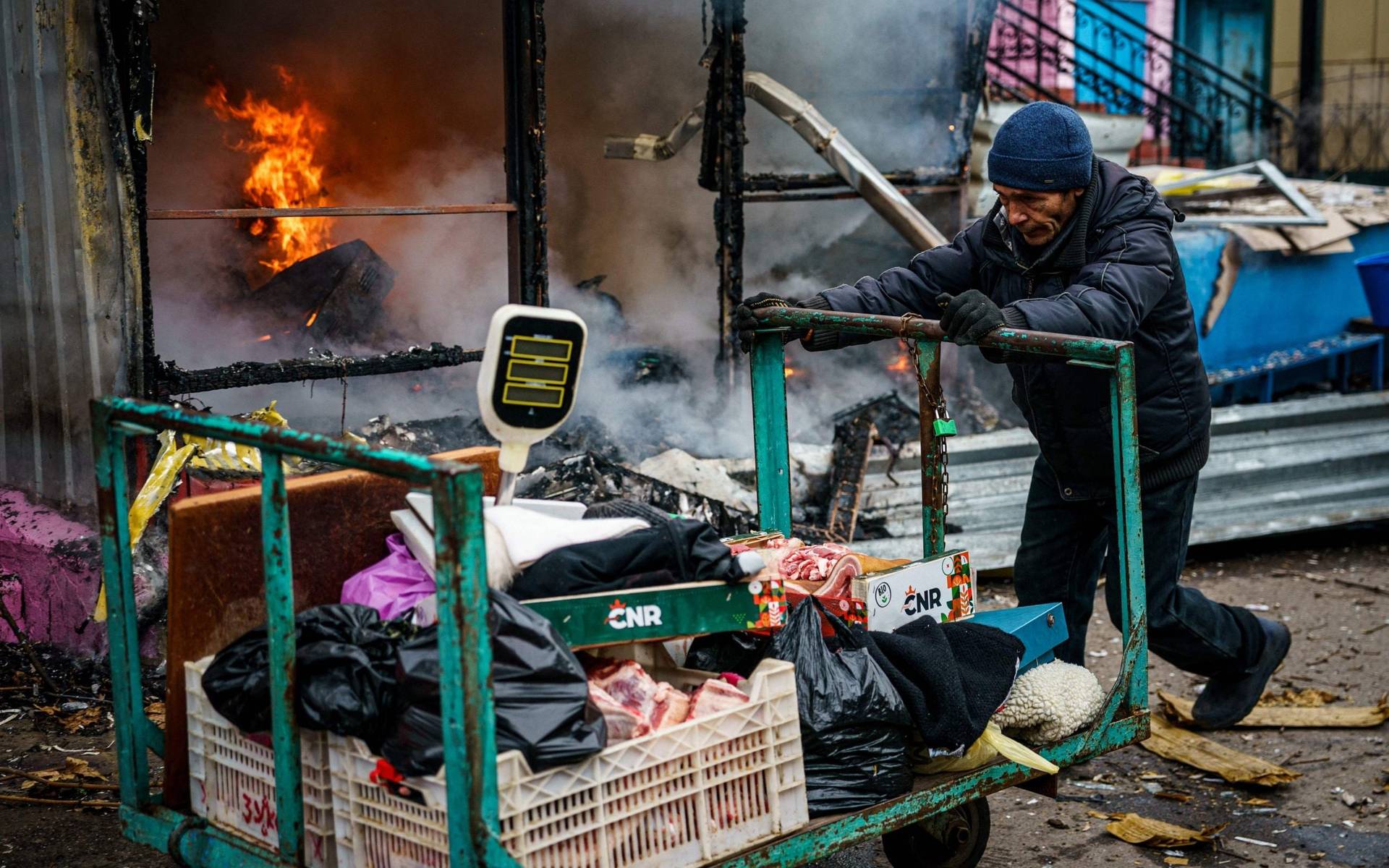 A man pushes a cart in front of a burning shop in Kherson on Saturday
