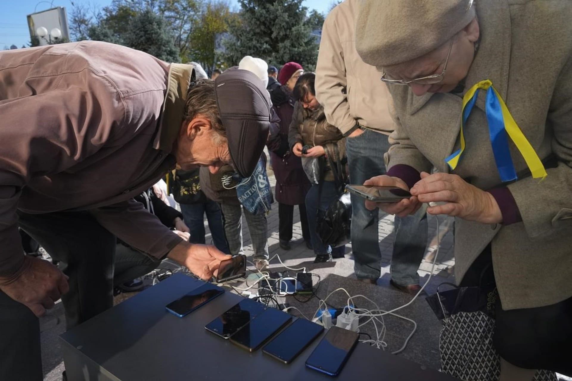 People charge their phones, try to connect to the internet and make phone calls, in central square in Kherson