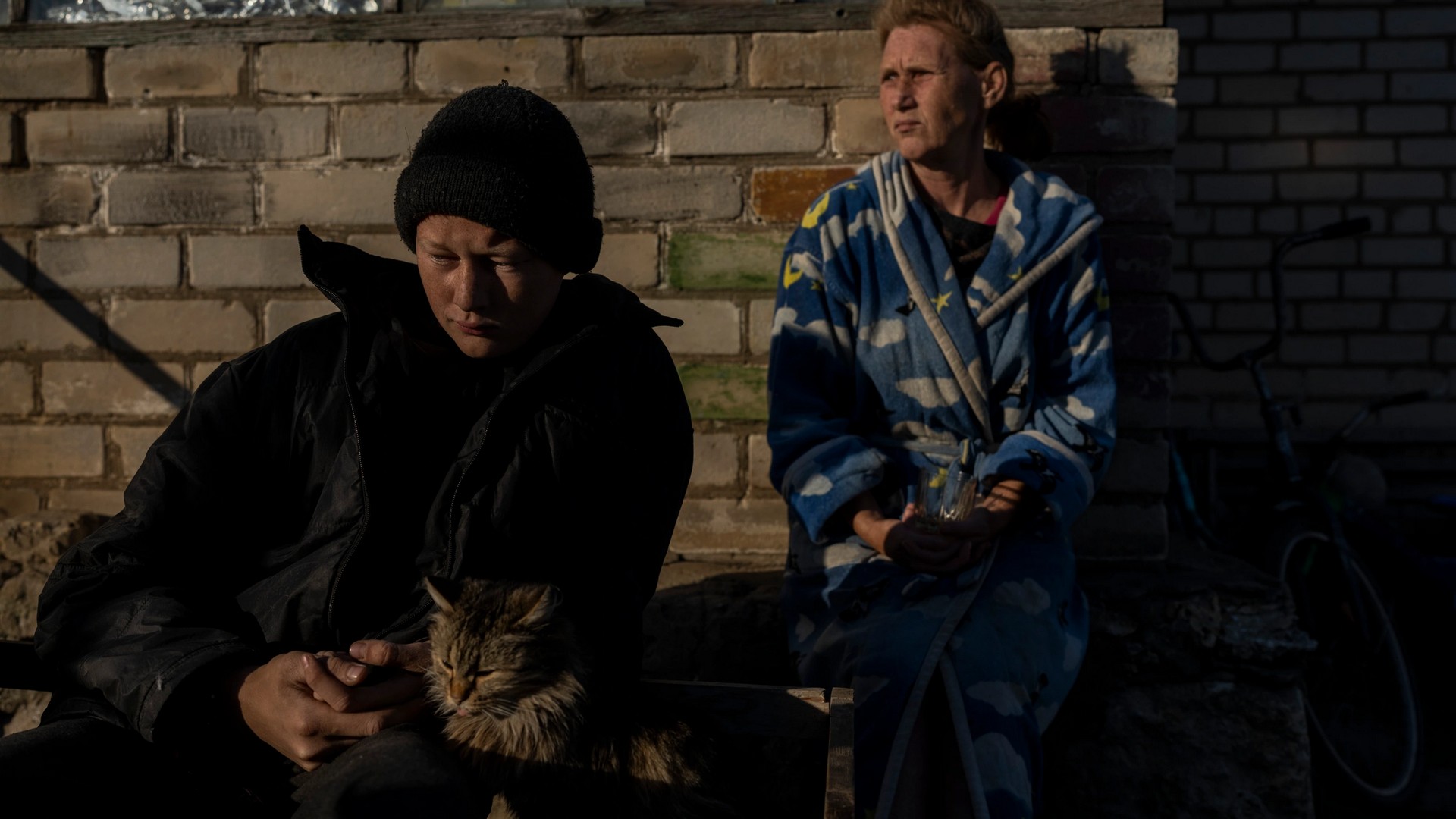 Vitaliy Mysharskiy and his grandmother Tanya Babii sit in the yard of the family house in the recently liberated village of Kyselivka