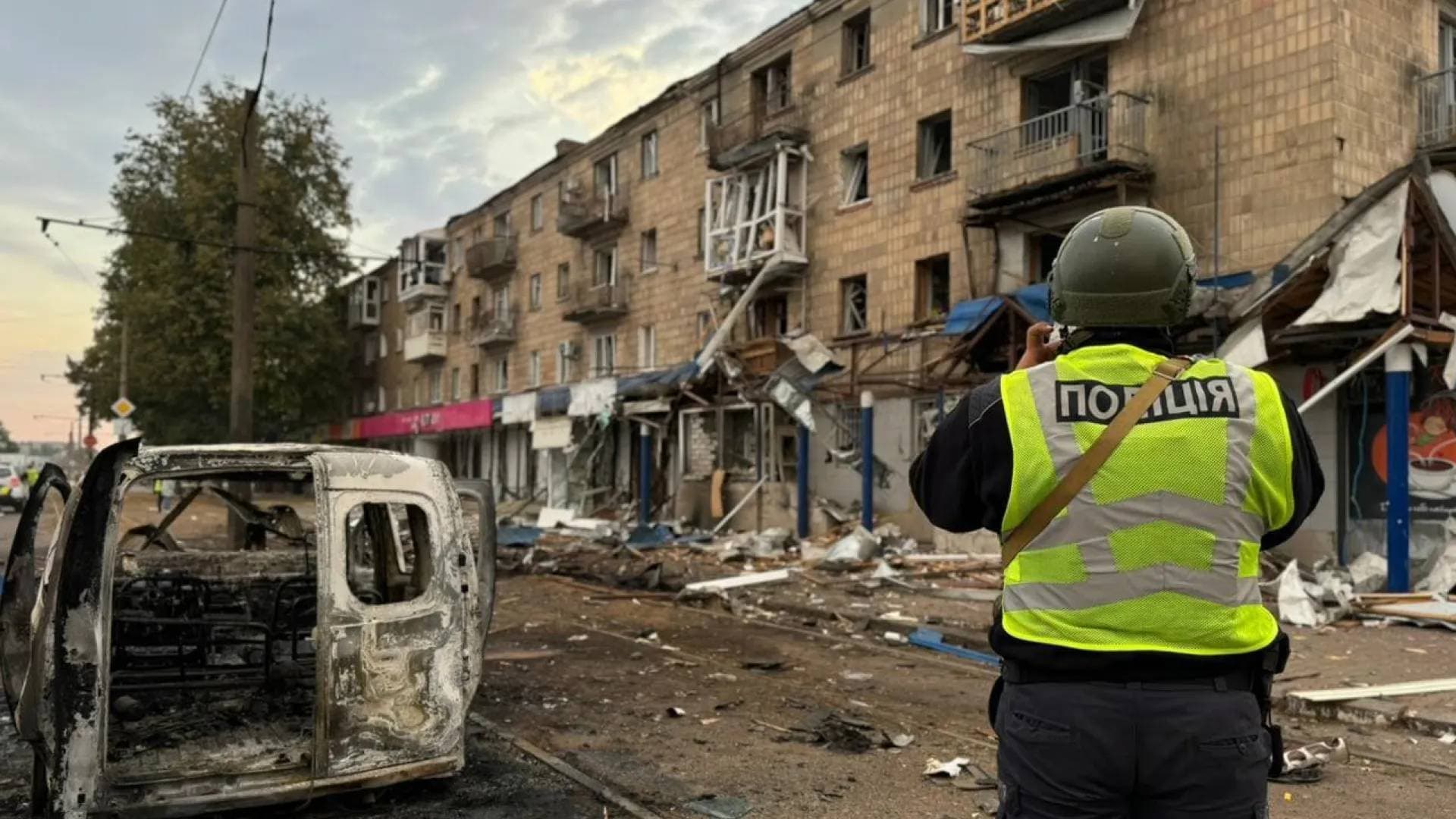 A police officer takes a picture of a residential building damaged during a Russian drone strike in Konotop