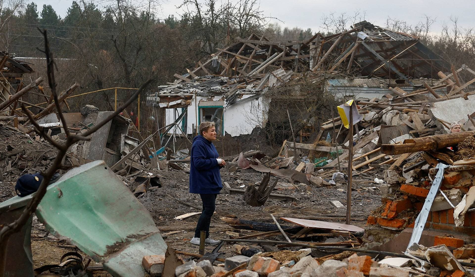 A resident stands next to her house, heavily damaged during a Russian missile strike in the town of Korosten
