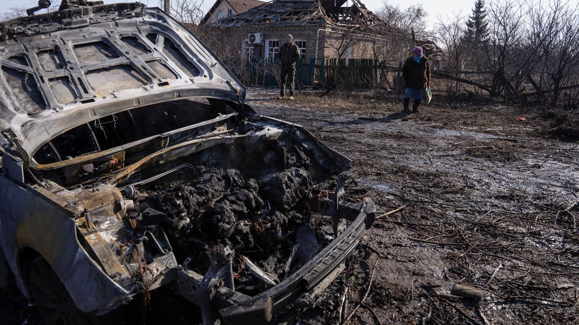 Residents stands next to a car destroyed by a Russian airstrike in Kramatorsk