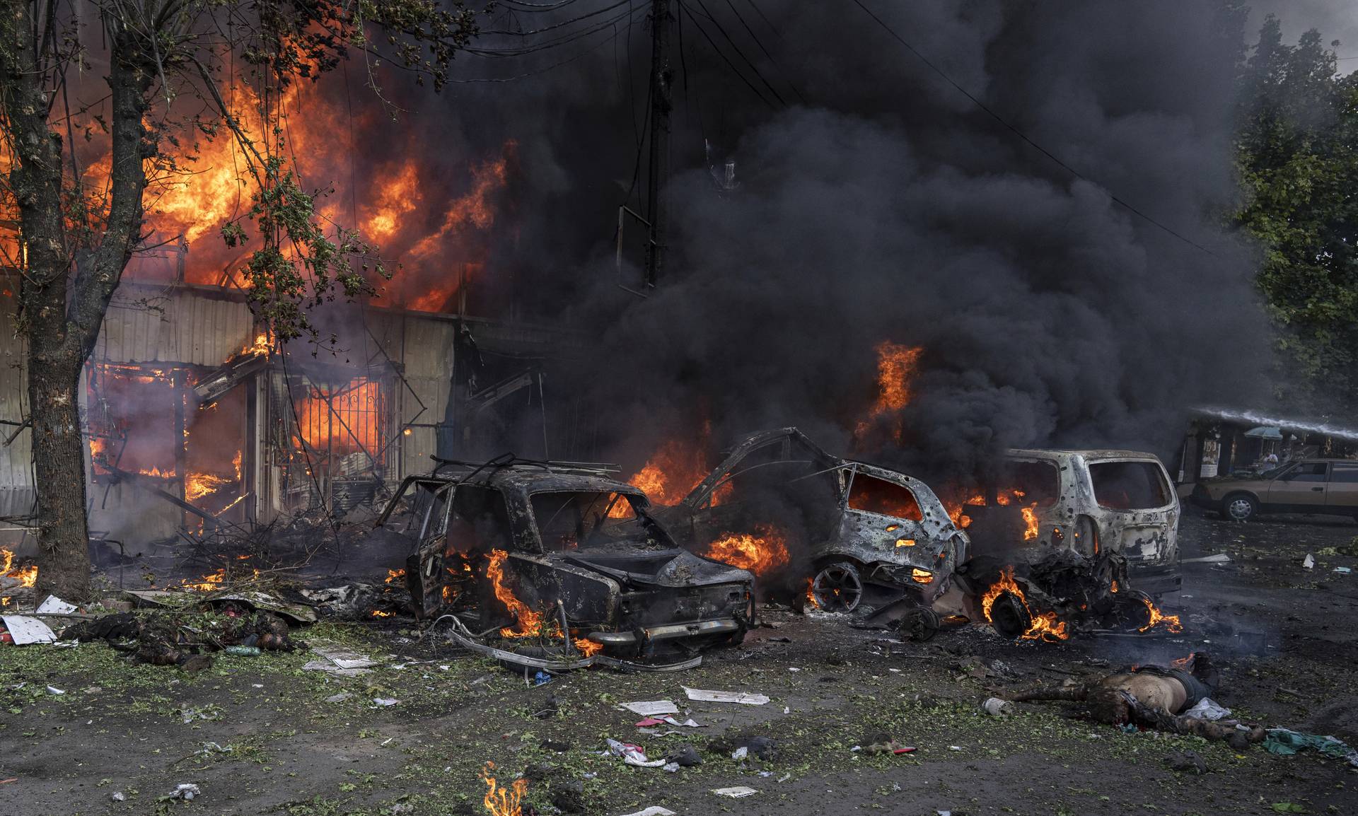 A dead body lays on the ground in front of a burning market after a Russian shelling attack in the city centrer of Kostiantynivka