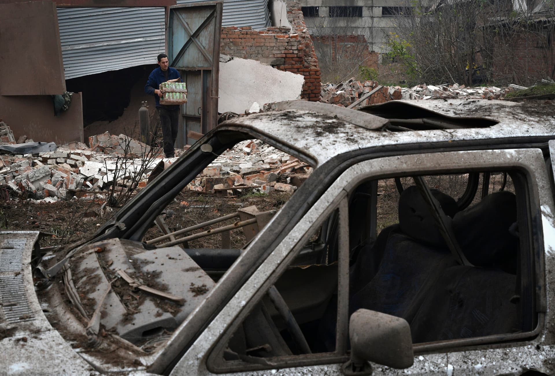A local resident taking out surviving small business property that was damaged after an overnight Russian attack in Kramatorsk