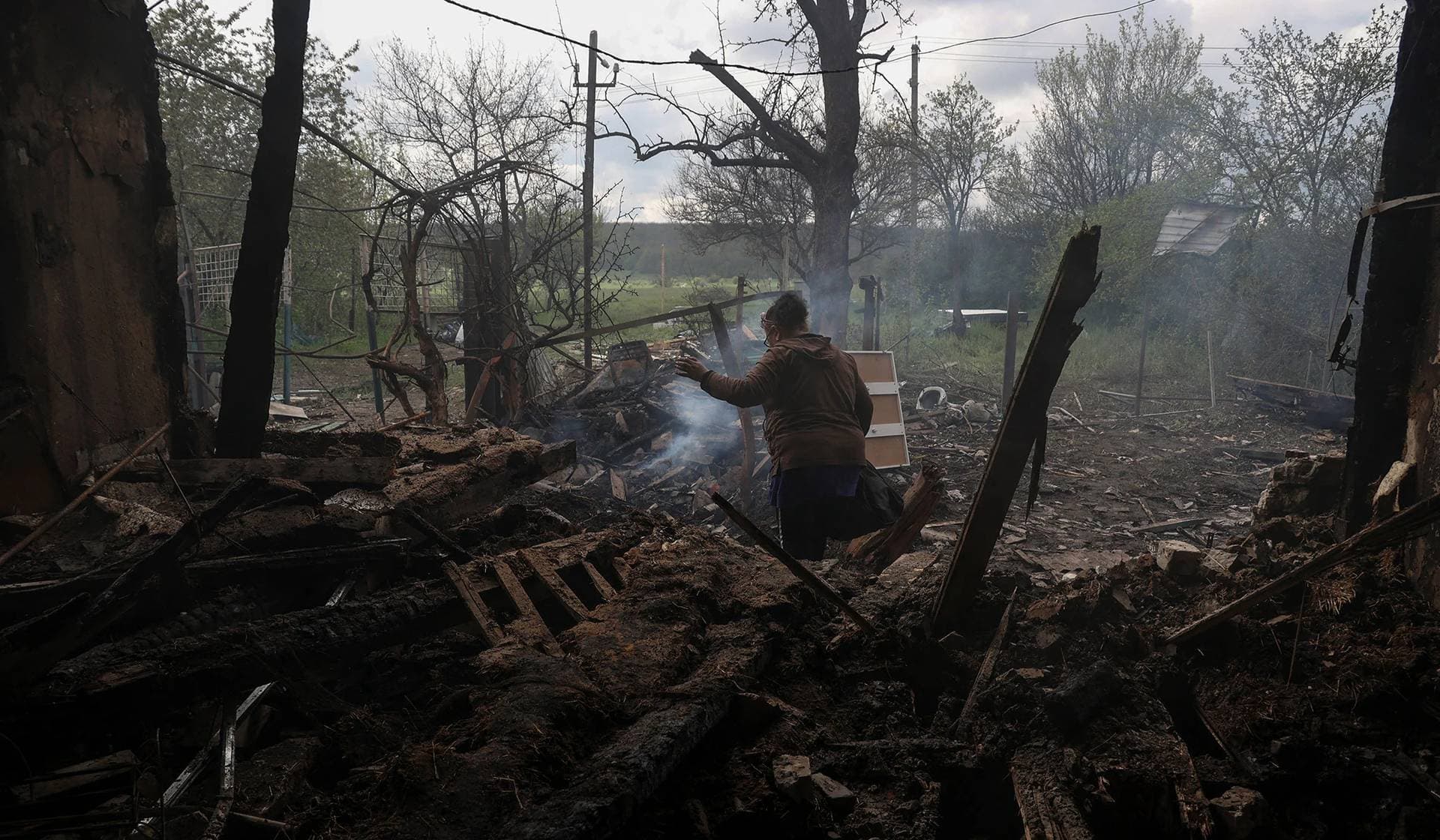 Tatiana Makohon carries items from a house of her friend destroyed by a Russian drone strike in the village of Malotaranivka