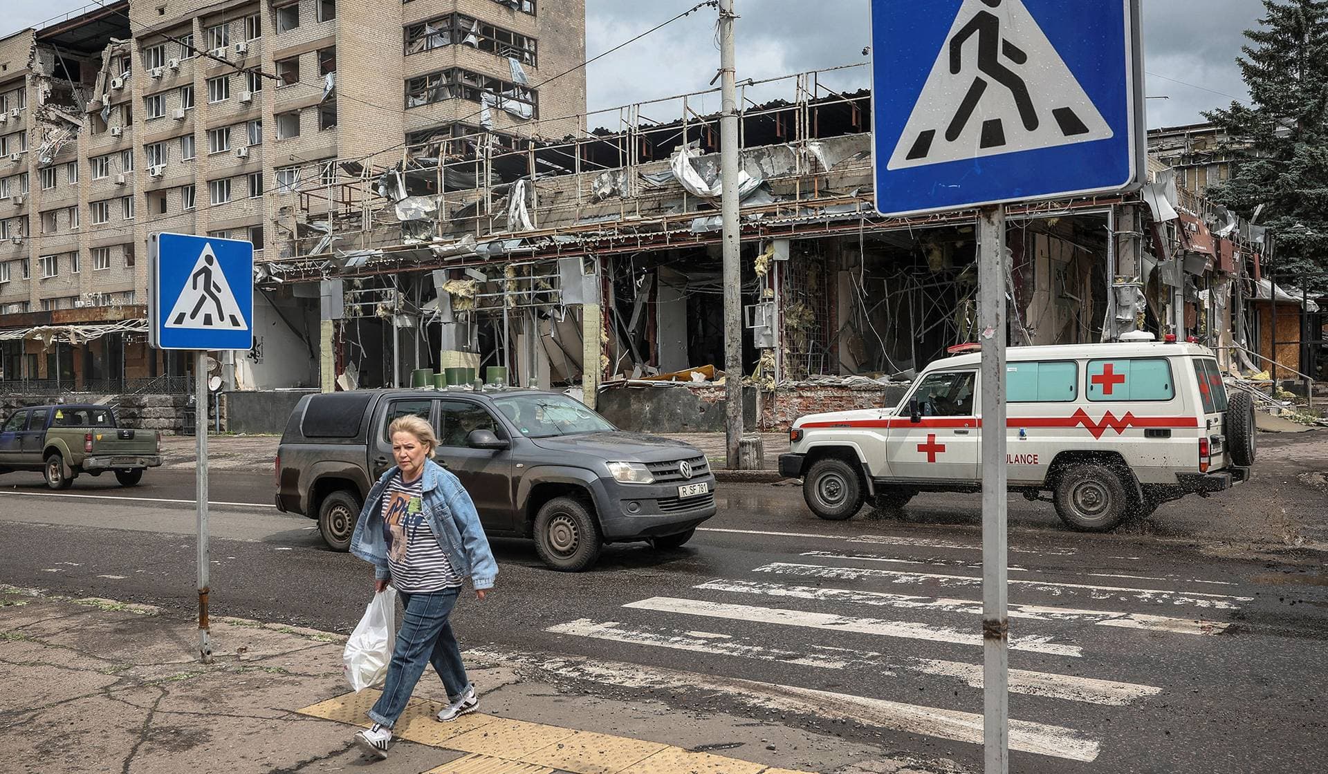 A woman crosses a street near a damaged building in the frontline city of Kramatorsk