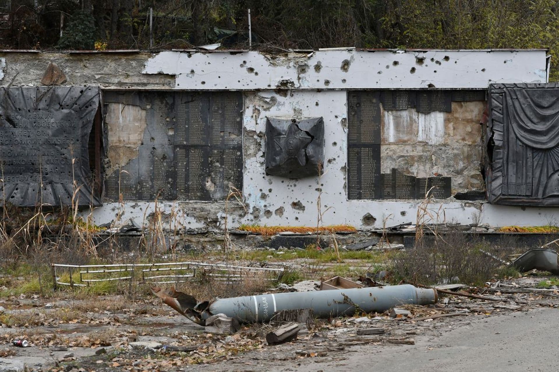 A part of a rocket lies in front of a WWII memorial damaged by fighting in the village of Dolyna