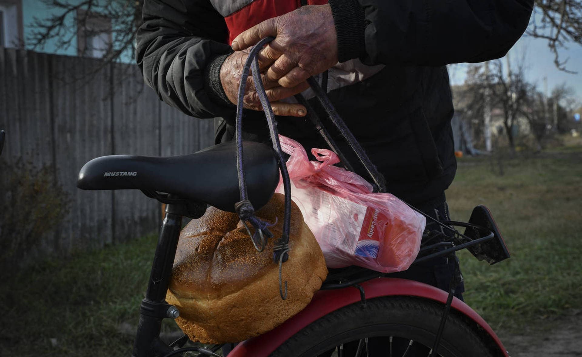 A local resident secures food on bicycle after receiving it at a mobile humanitarian aid point in the village of Zarichne