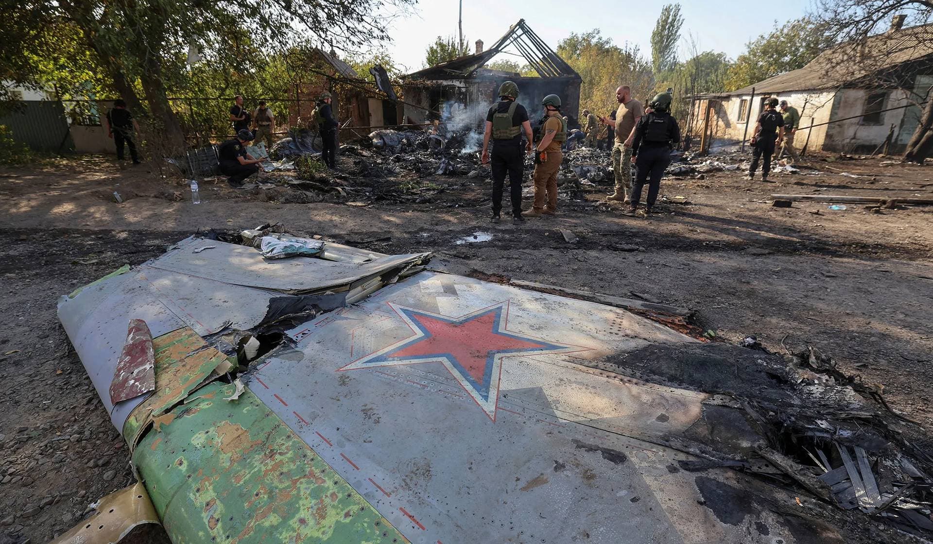 Ukrainian service members inspect parts of a Russian aerial vehicle in a residential area of Kostintynivka