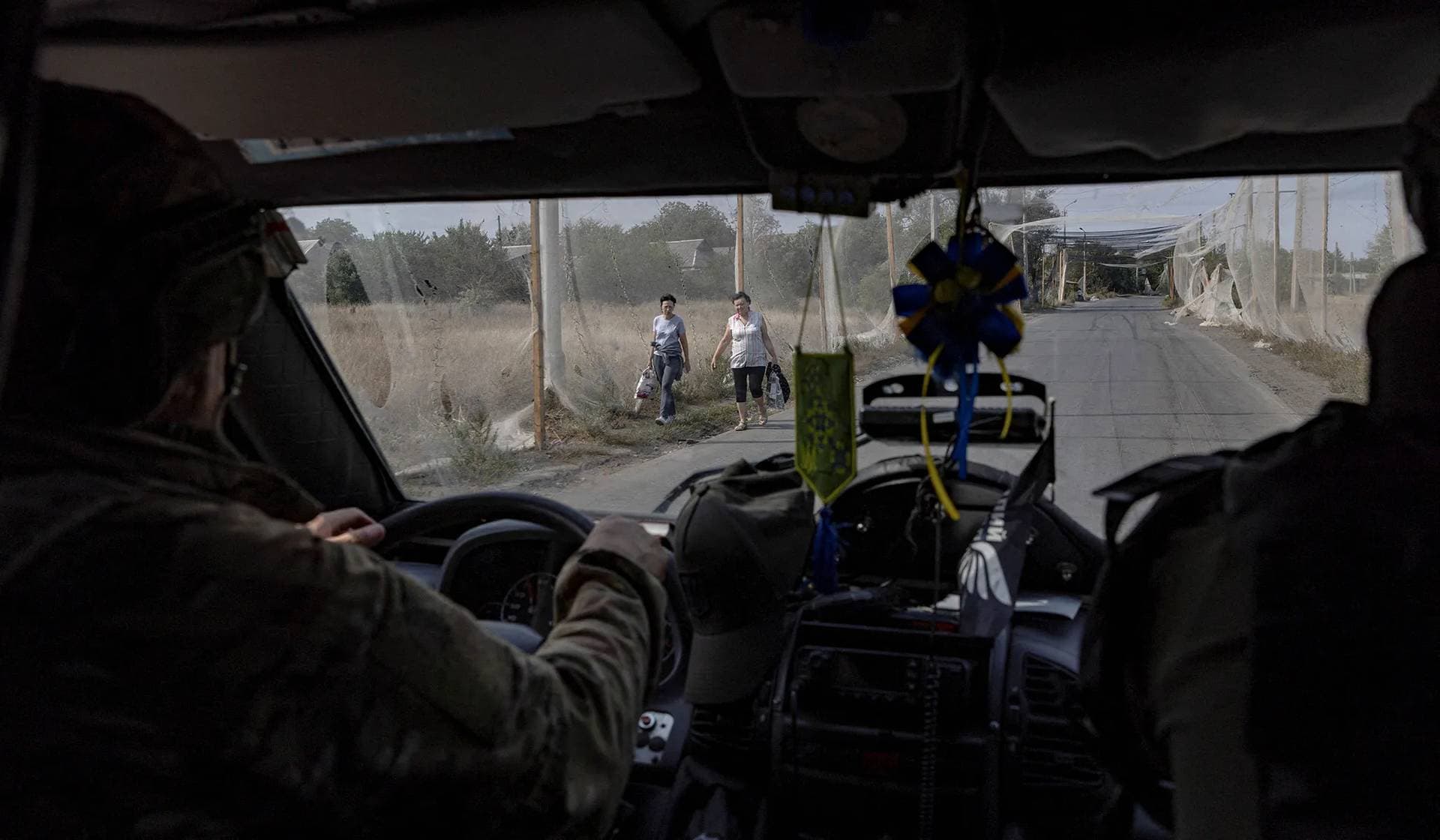 Member of the White Angels police evacuation unit drive an armoured van along a street covered with an anti-drone net during an evacuation of residents from the frontline town of Kostiantynivka