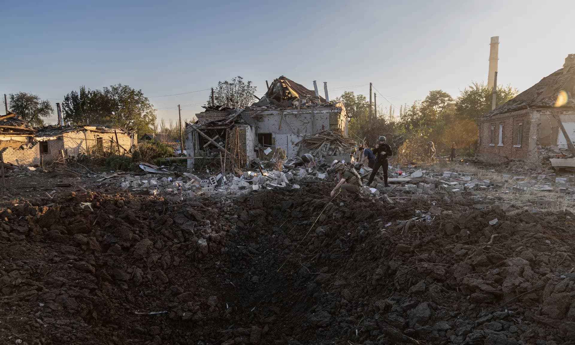 Police officers examine a crater from a Russian rocket at the residential neighbourhood in Kostiantynivka