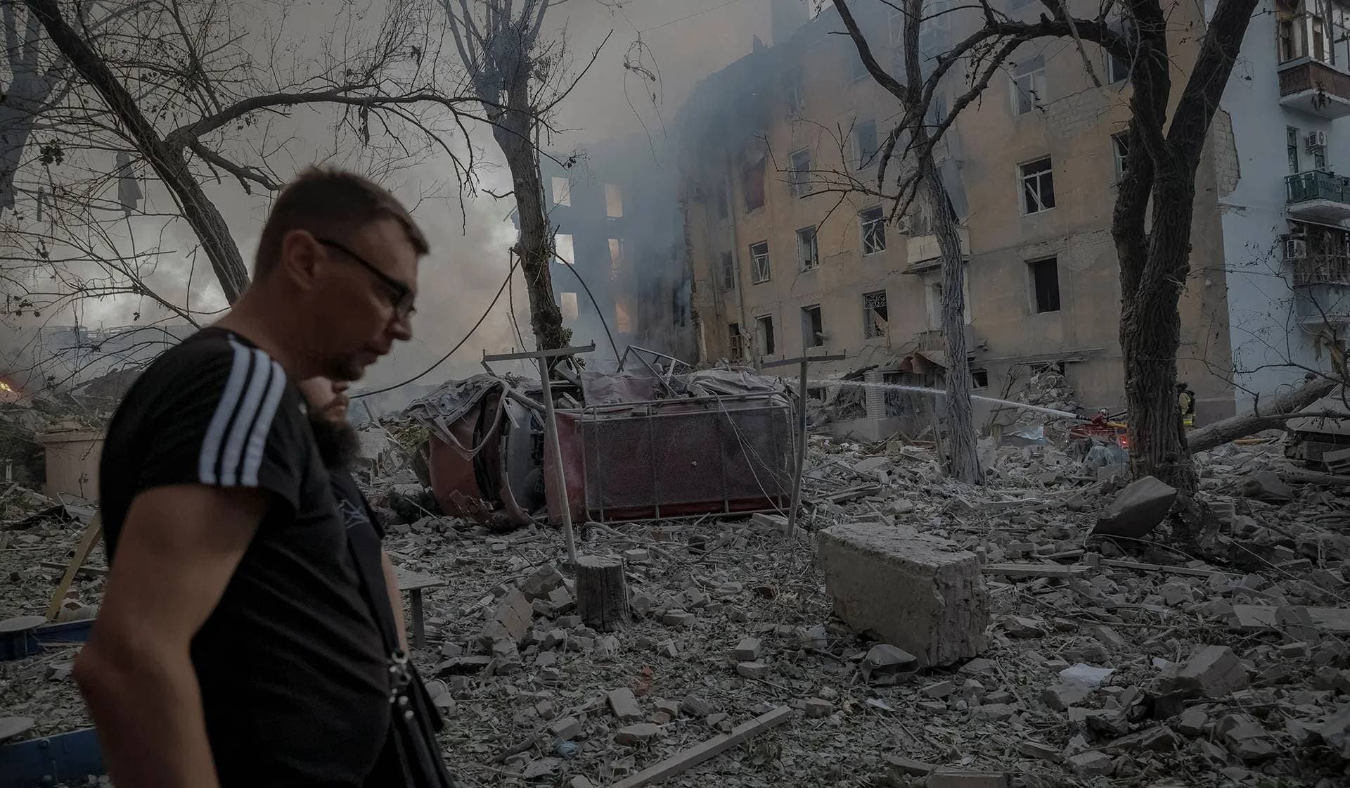 Residents walk at the site of an apartment building hit by a Russian military strike in Kramatorsk