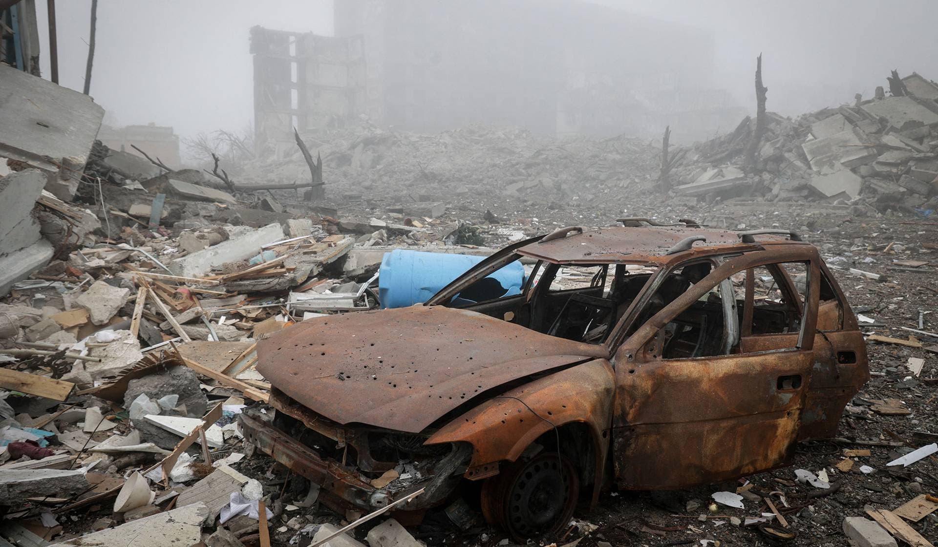 A destroyed car lies near apartment buildings damaged by Russian military strike in the frontline town of Kostiantynivka