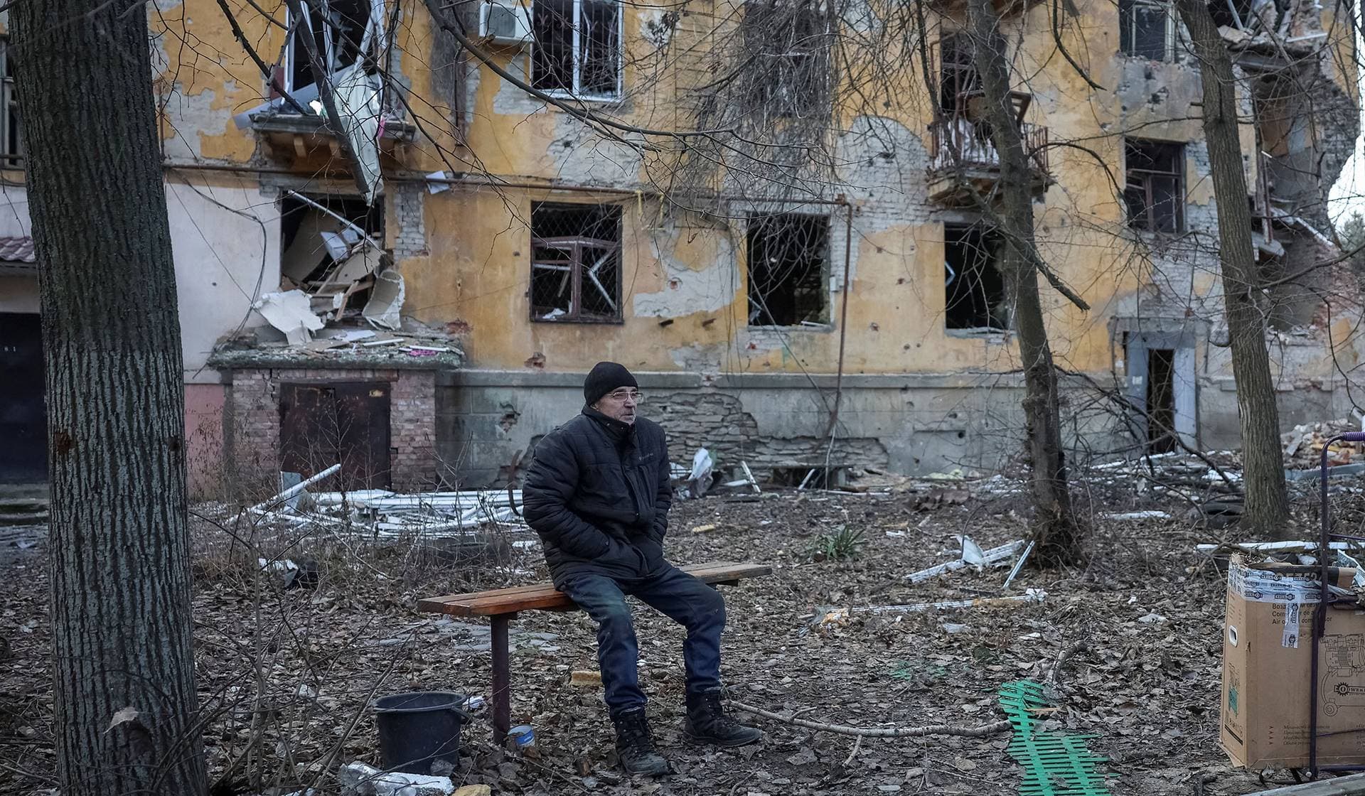 A resident sits near an apartment building damaged by Russian military strike in the frontline town of Kostiantynivka