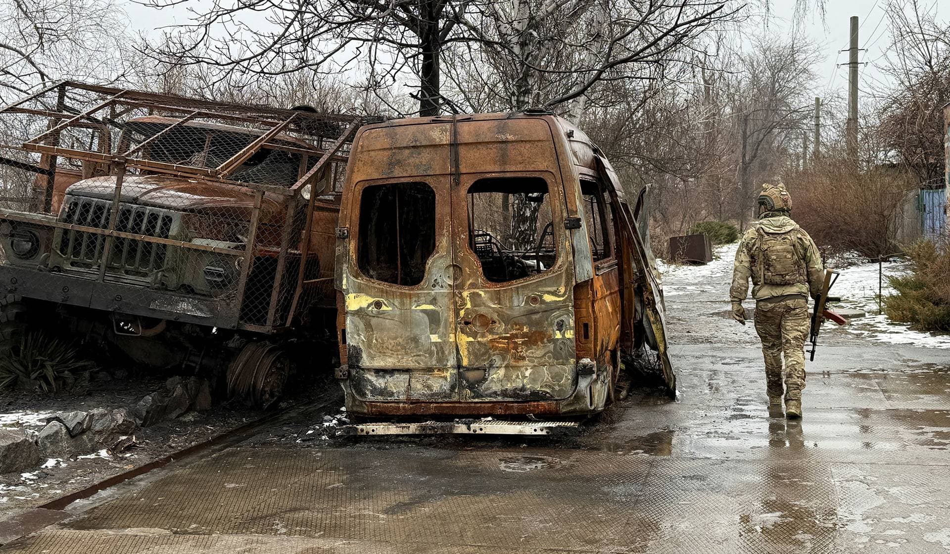 A service member of the Ukrainian Armed Forces walks on a road near destroyed cars in the frontline town of Kostiantynivka