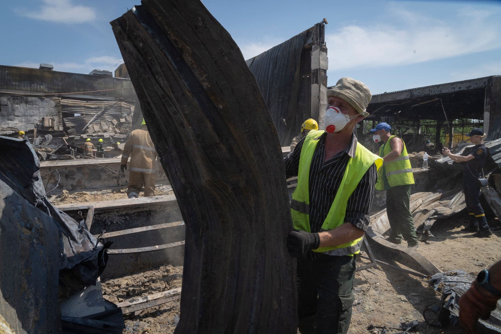 Workers clear debris at a shopping center that was damaged in a Russian rocket attack in Kremenchuk