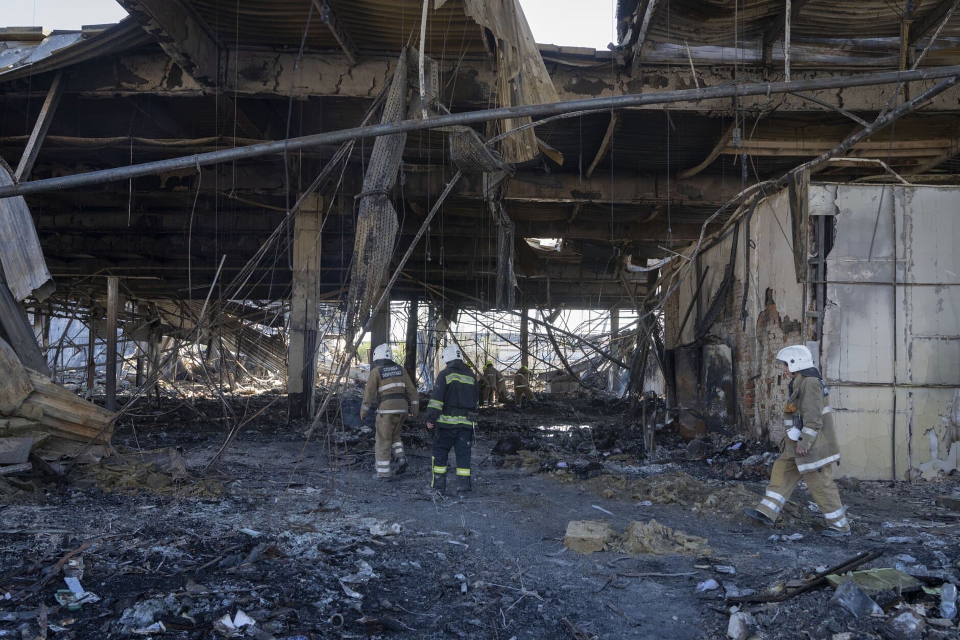 Ukrainian State Emergency Service firefighters work to take away debris at a shopping center burned after a rocket attack in Kremenchuk