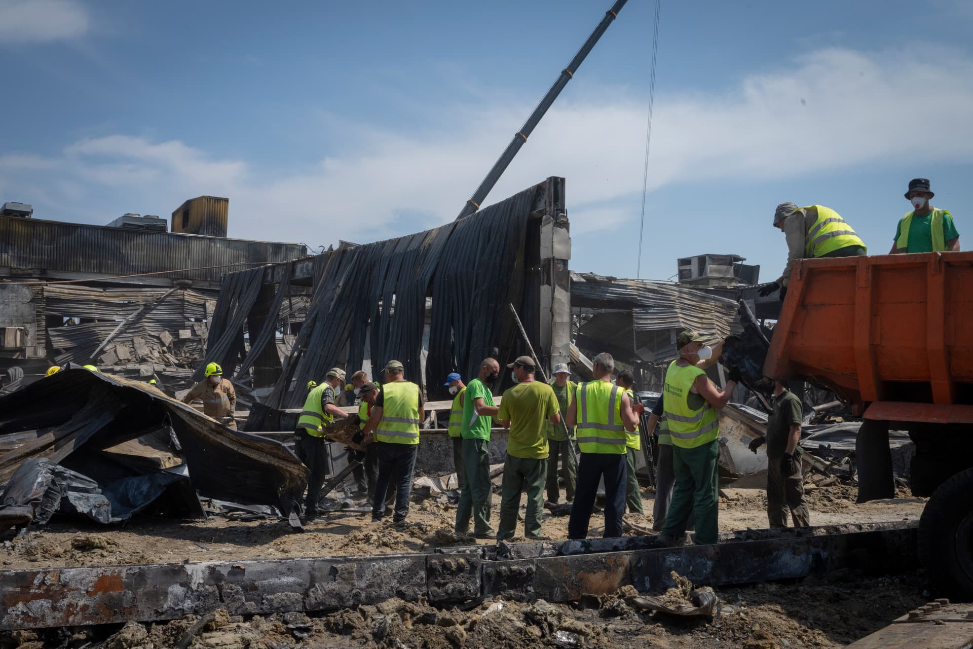 Workers clear debris at a shopping center that was damaged in a Russian rocket attack in Kremenchuk
