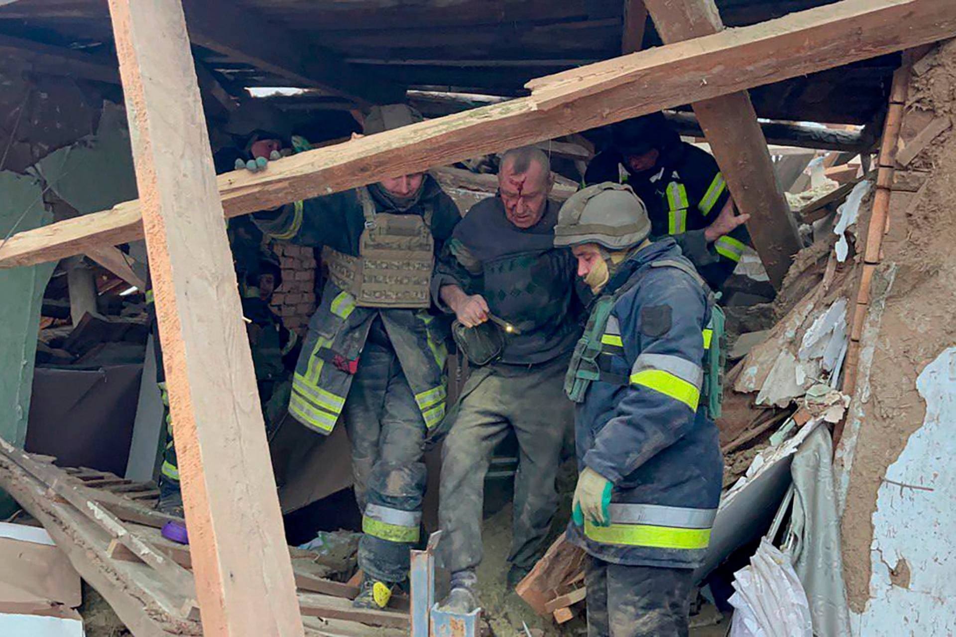 emergency workers help a wounded man after a residential houses were badly damaged in a Russian missile attack near Kryvyi Rih