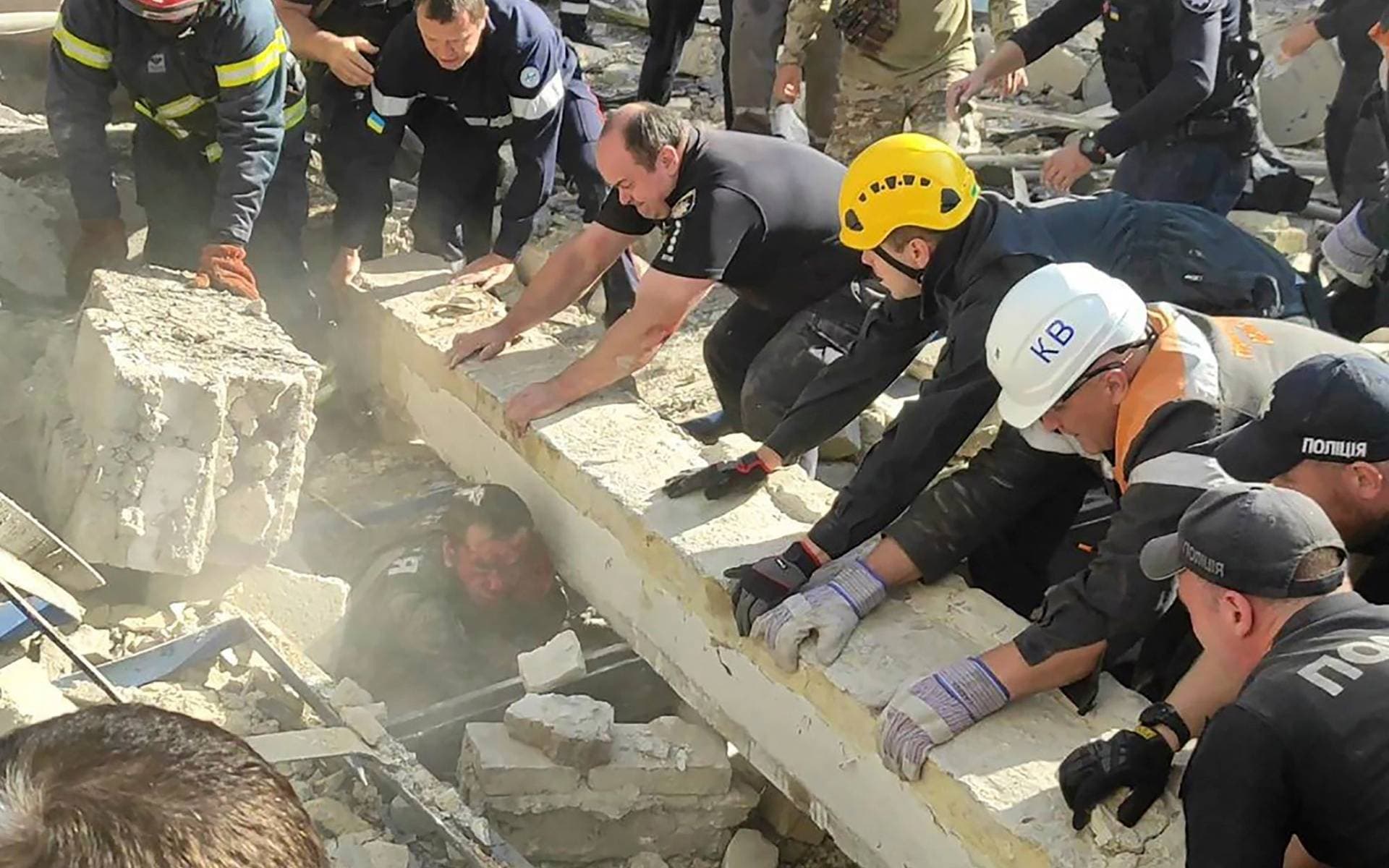 Emergency services and policemen work to save an injured police officer from under the rubble following a Russian attack in Kryvyi Rih