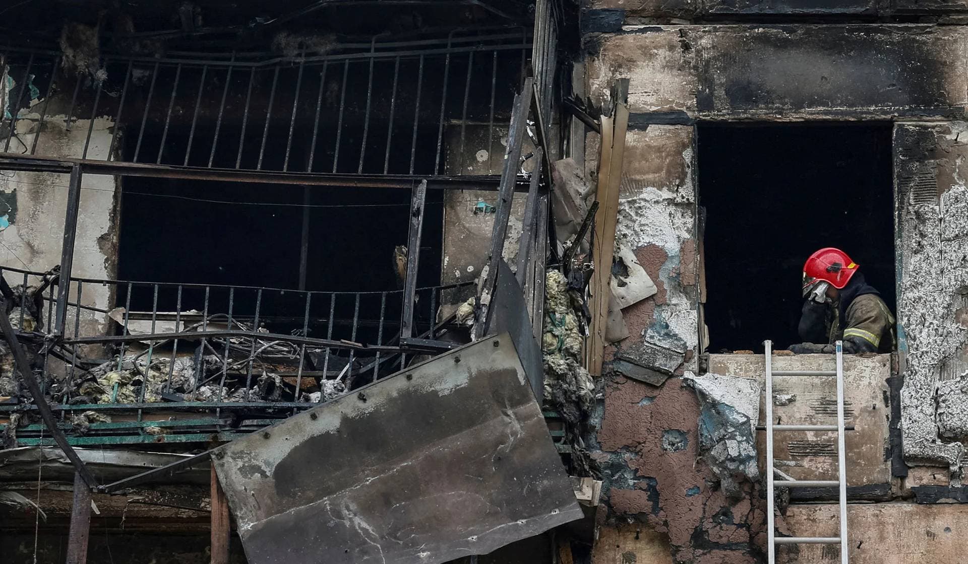 A rescuer wipes their face while working in a residential building heavily damaged by a Russian missile strike in Kryvyi Rih