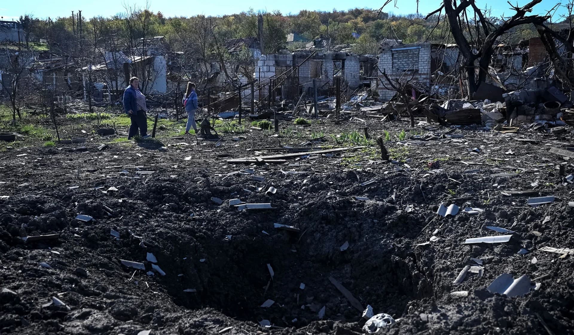 Local residents Natalia and her granddaughter Ilona stand on ruins of their house in Kupiansk Vuzlovyi