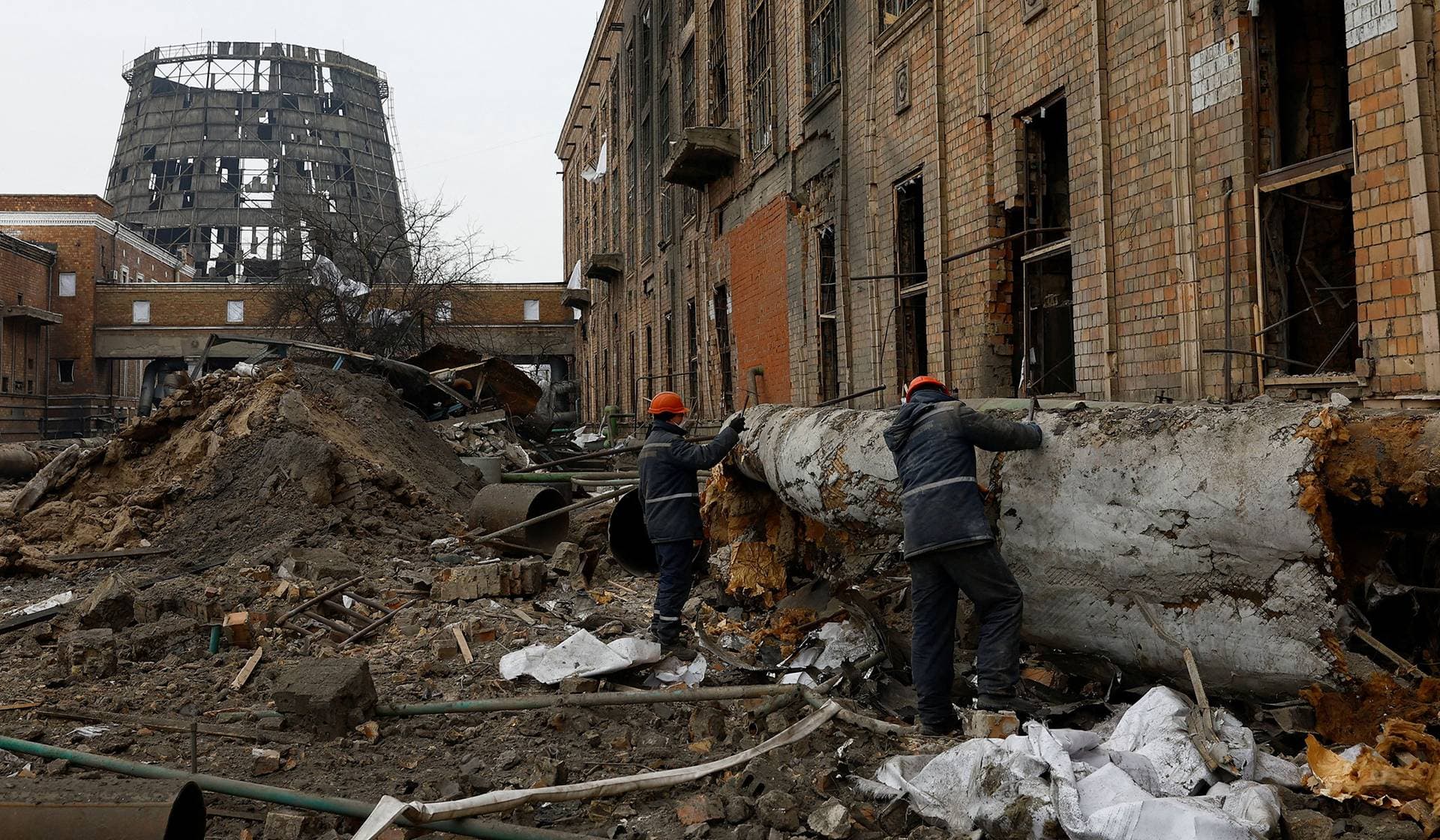 Workers remove insulation from a pipe at a compound of the Darnytsia Thermal Power Plant, which was heavily damaged by recent Russian missile and drone strikes in Kyiv