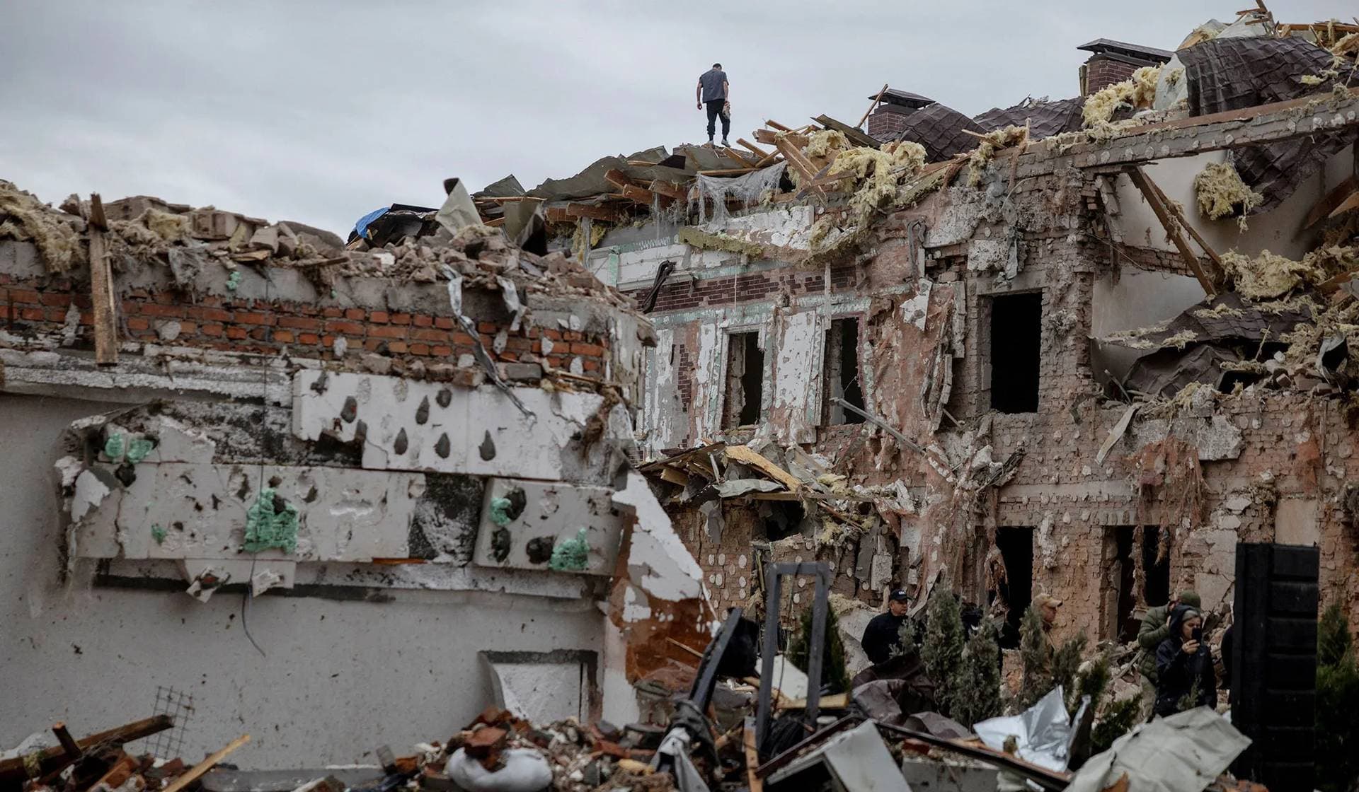 A man stands on a roof of destroyed residential buildings that were hit during Russian drone and missile strikes in Kyiv