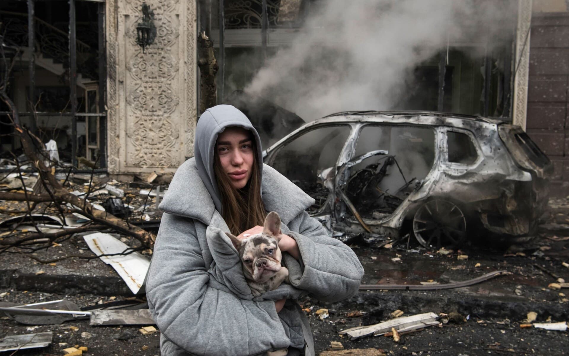 A woman holds a dog in front of a damaged building after Russia's missile attack on Kyiv