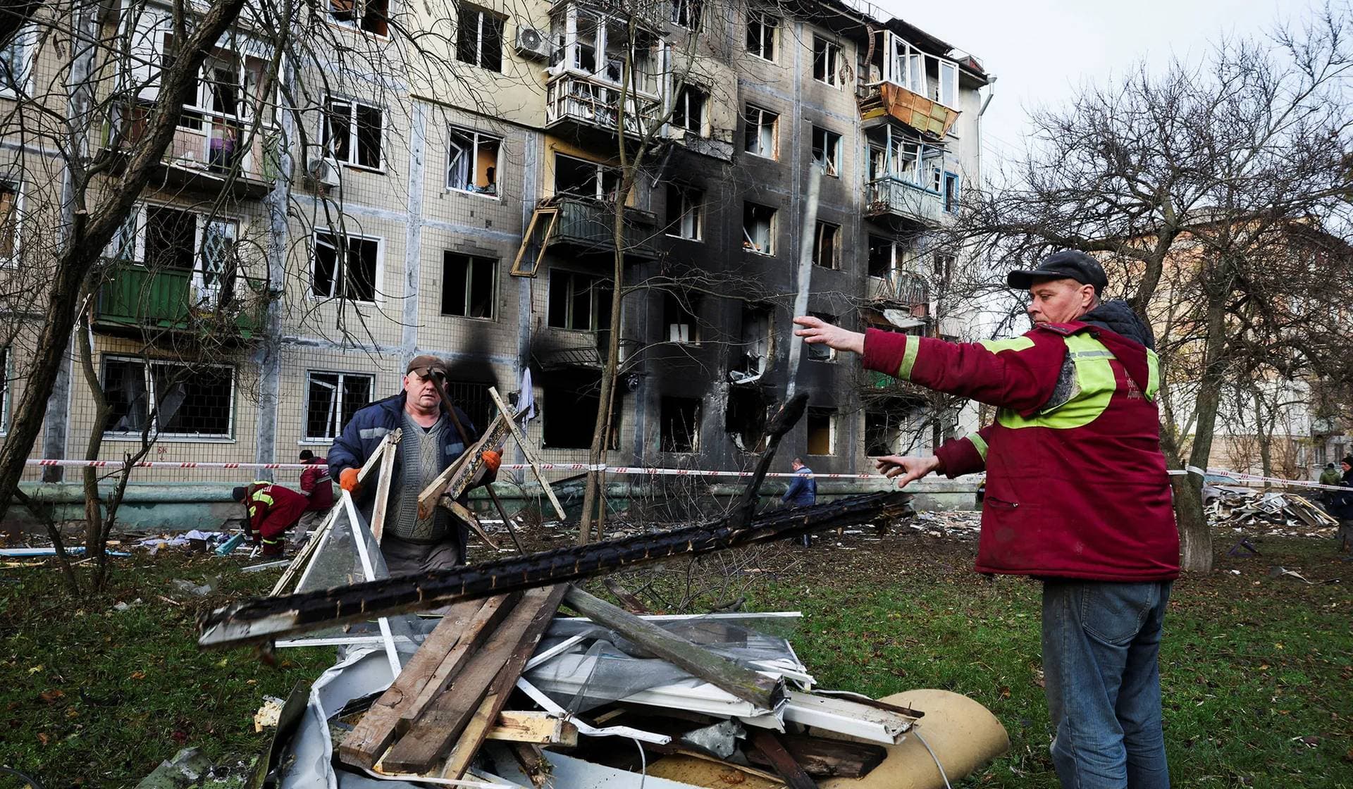 Workers clean up debris, outside an apartment building damaged during an overnight Russian drone and missile strike in Kyiv