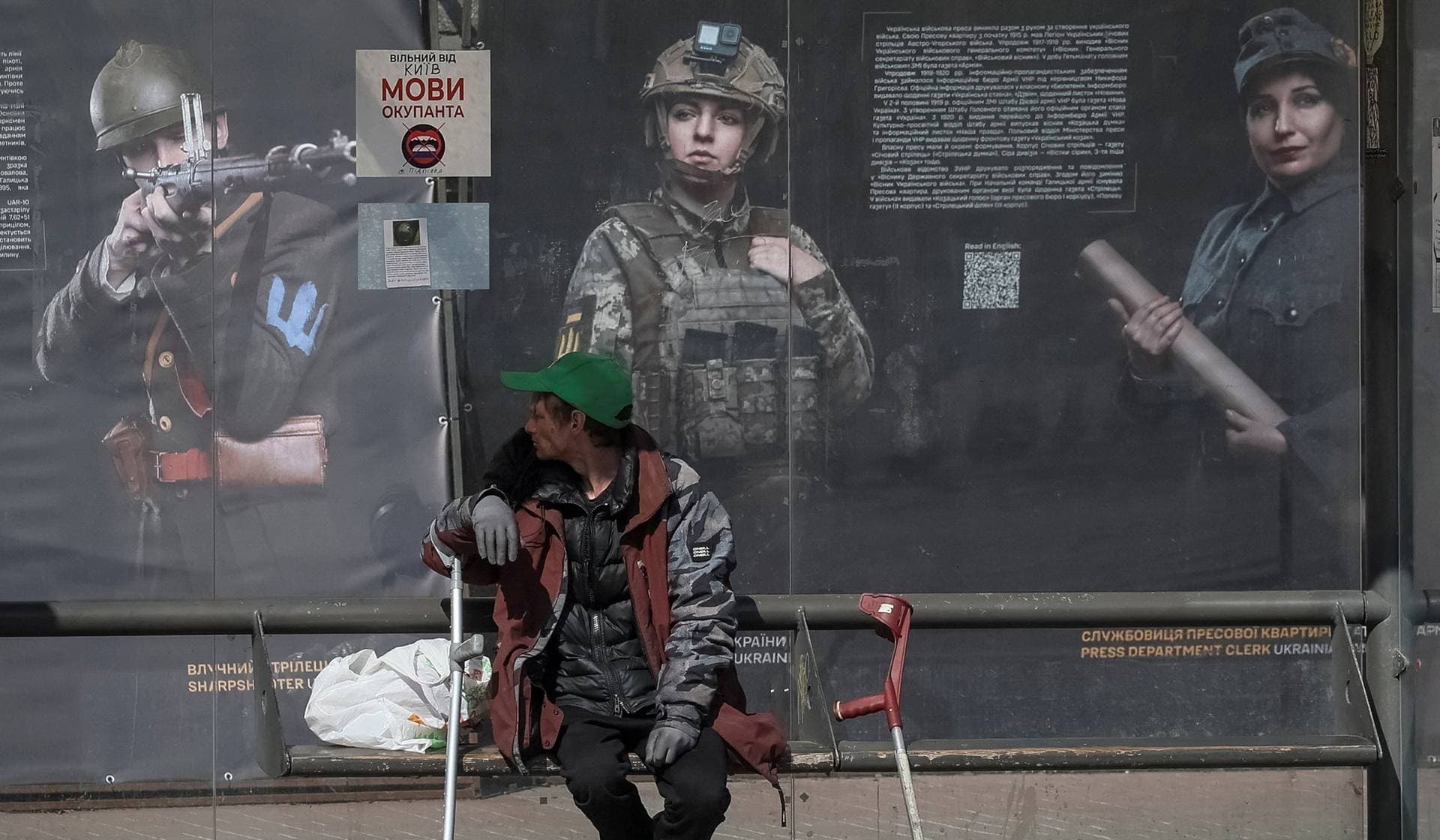 A man sits at a public transport stop in Kyiv