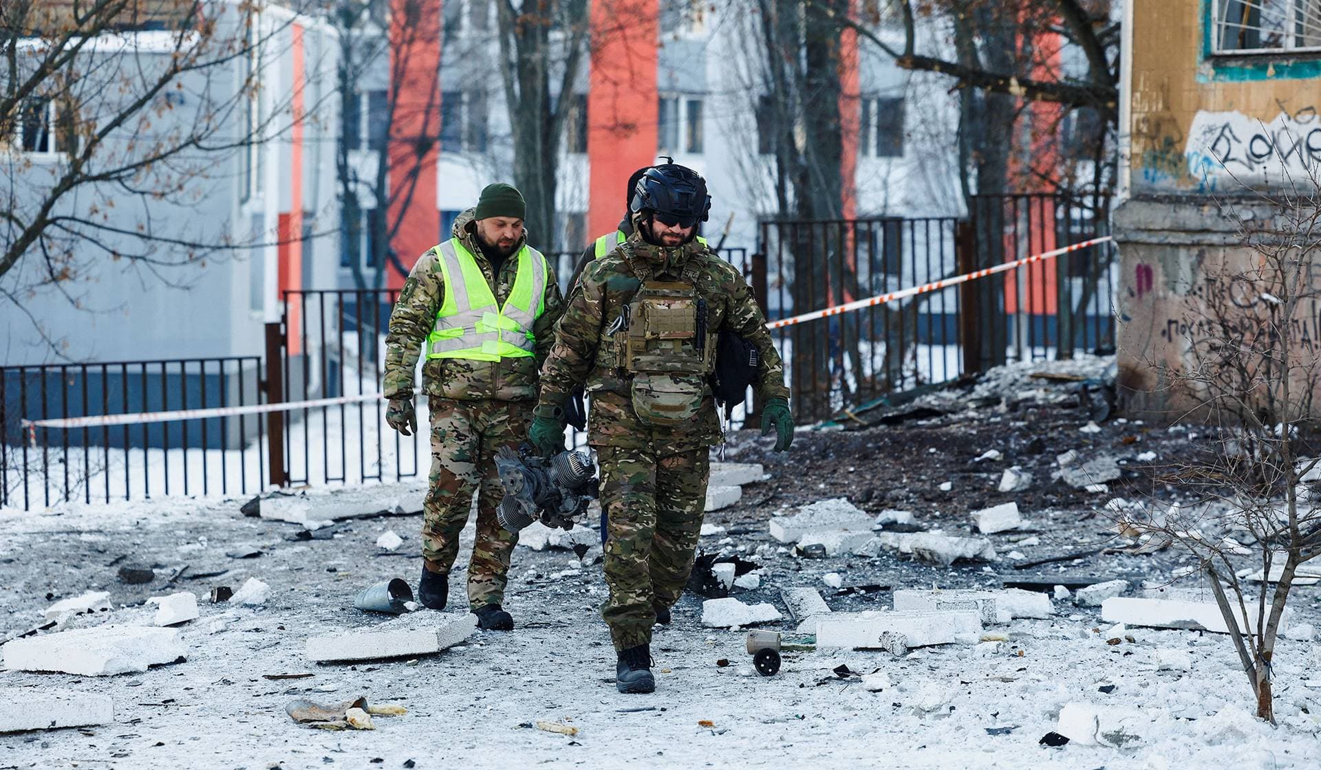 A police officer carries a part of a Russian suicide drone that was found at the site of an apartment building hit by one in Kyiv