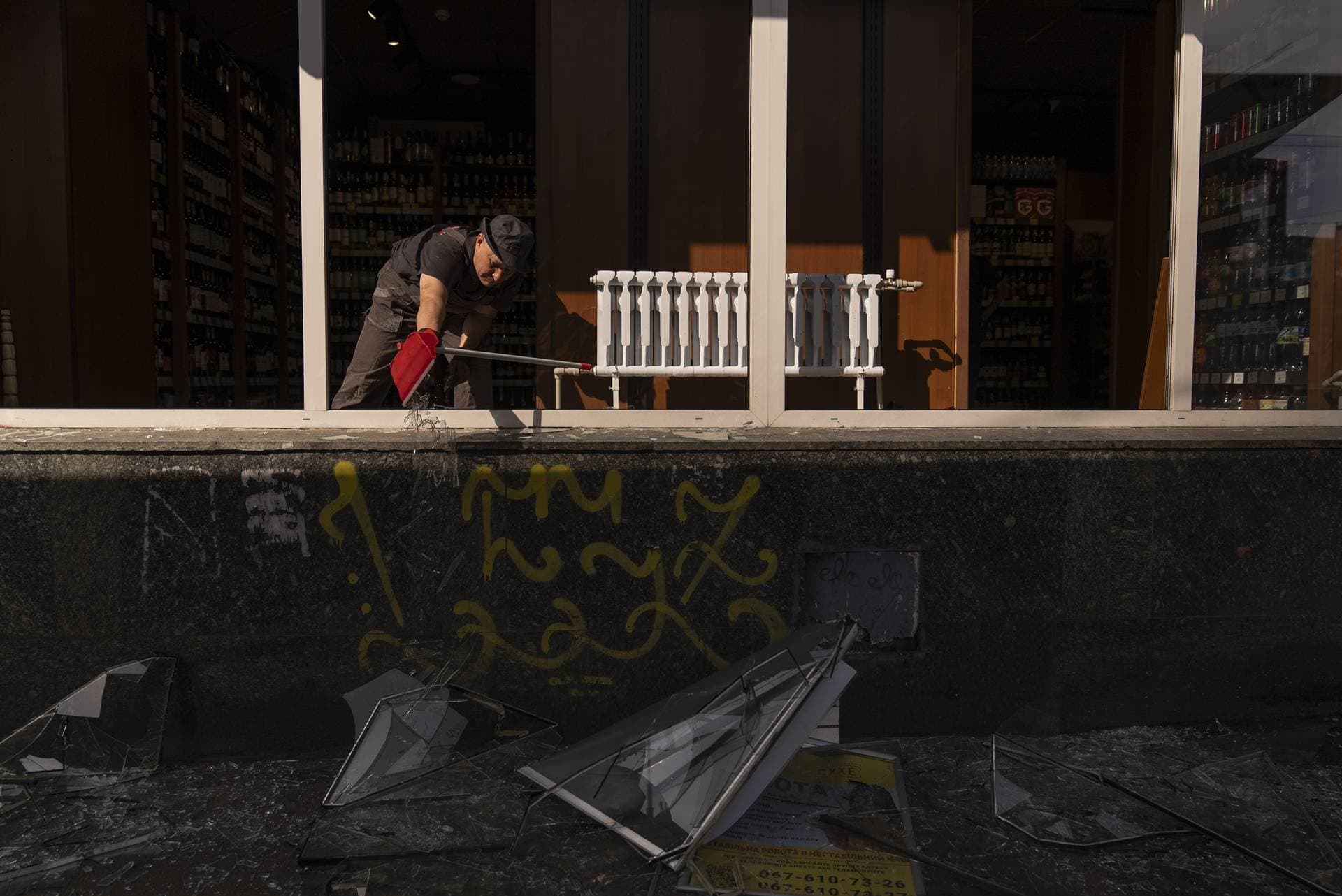 A man cleans up debris at a damaged liquor store in Kyiv