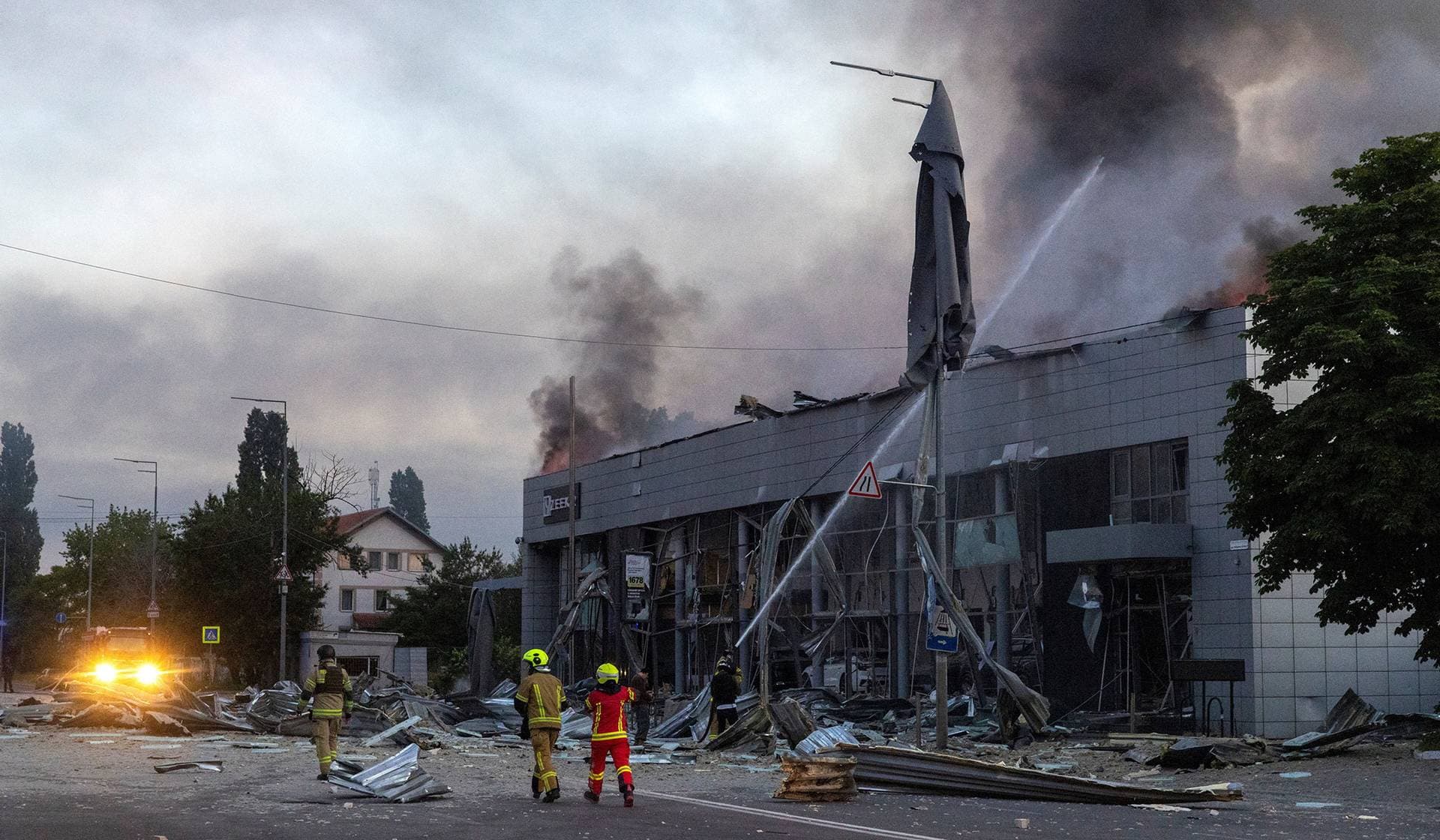 Emergency workers respond to a fire in a car dealership that was struck during overnight Russian missile and drone attacks in Kyiv