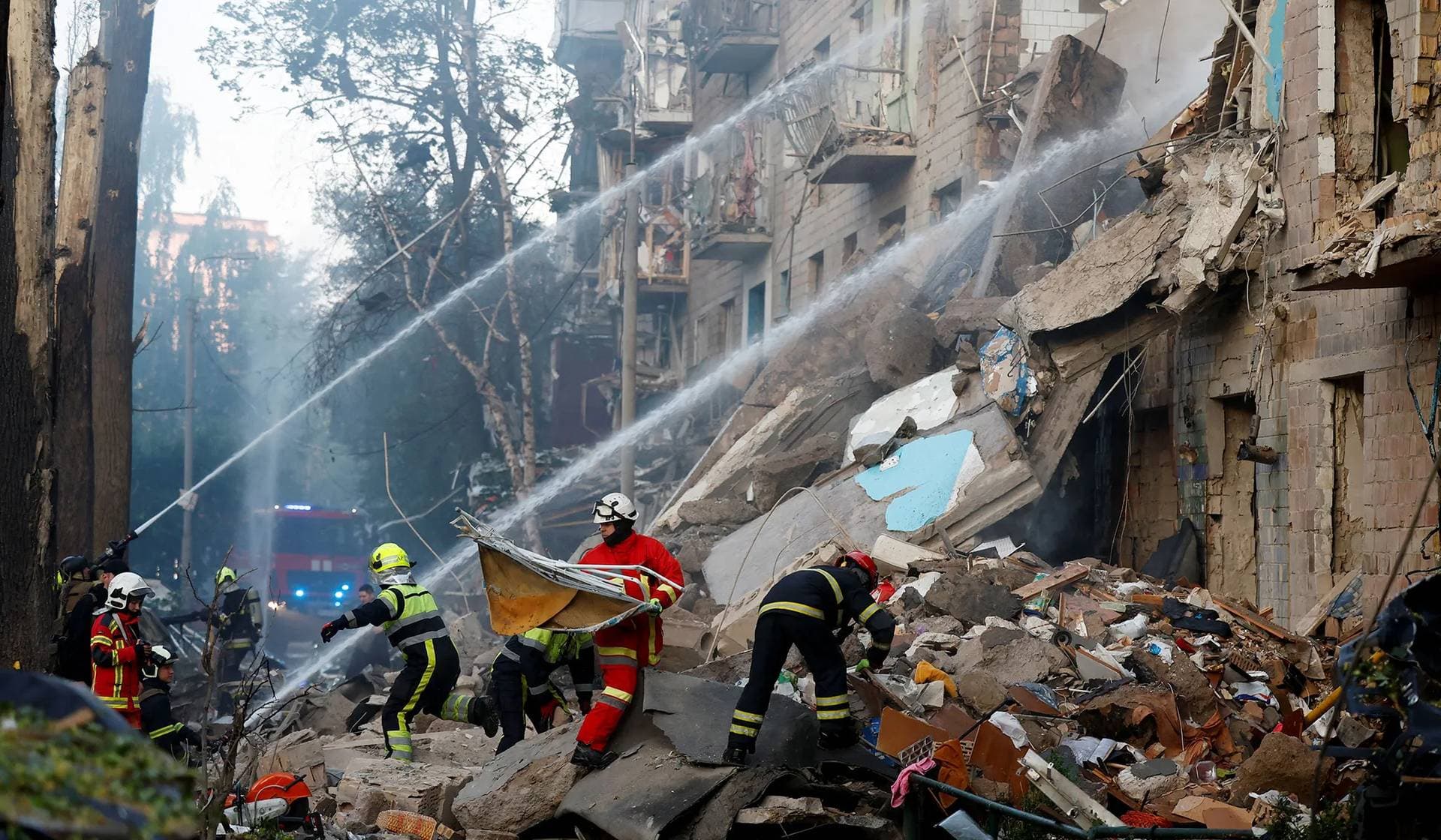 Firefighters work at the site of an apartment building hit during Russian drone and missile strikes in Kyiv