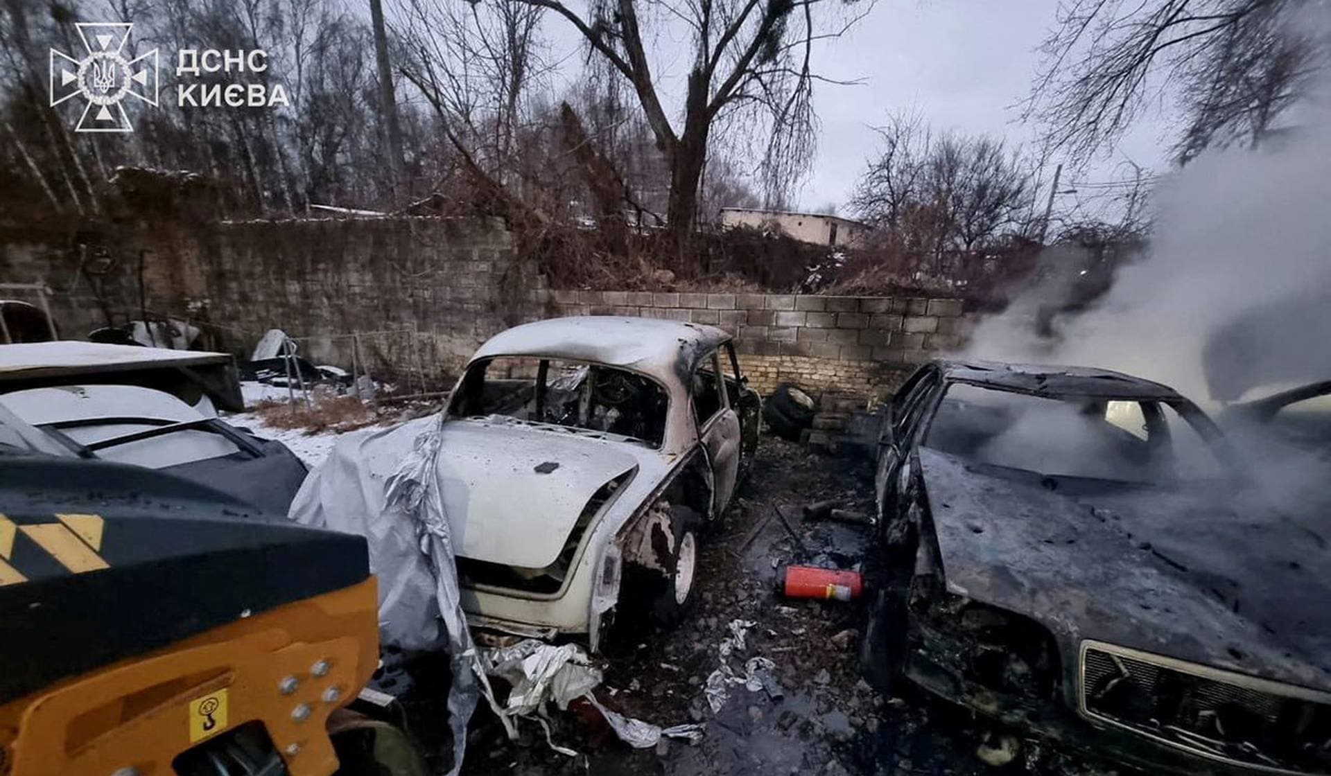 Smoke rises from a burnt car at the site of a repair workshop damaged during Russian missile and drone strikes in Kyiv