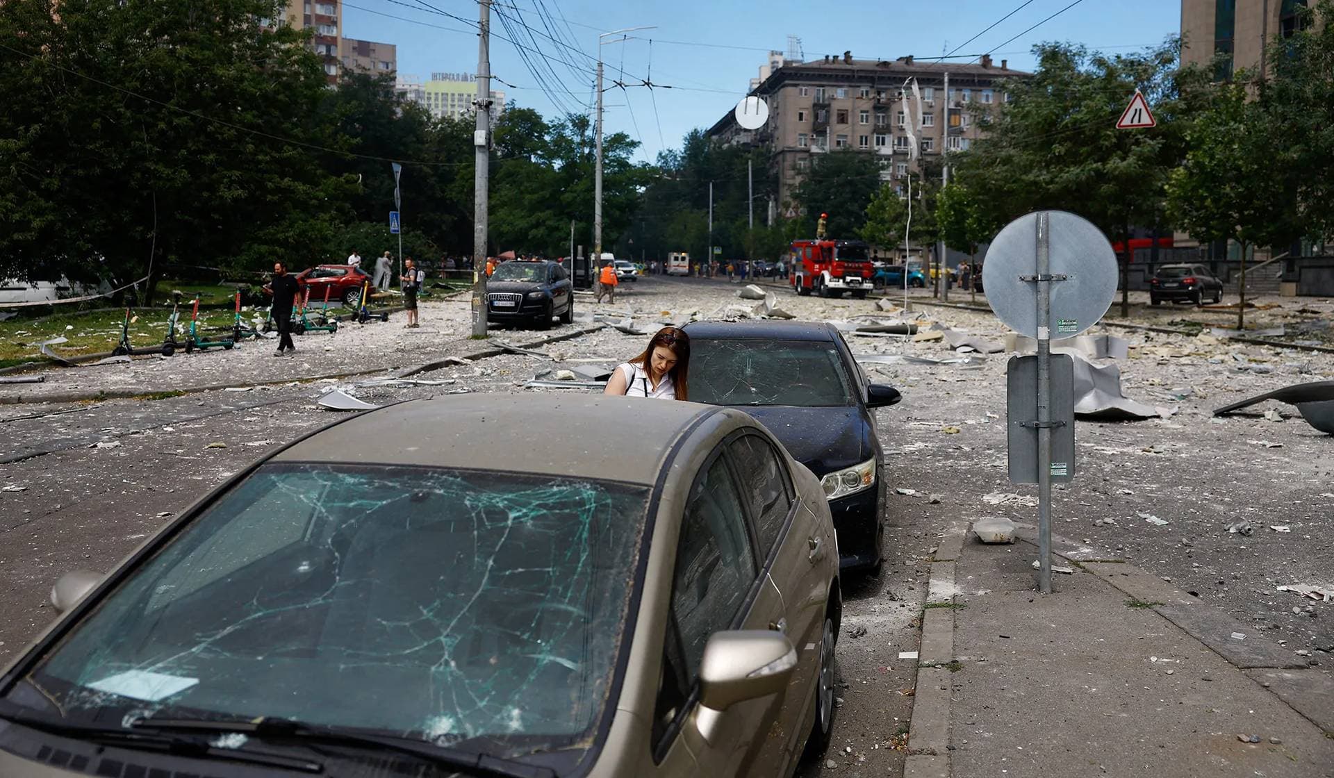 A woman checks her car which was damaged during Russian missile strikes in Kyiv