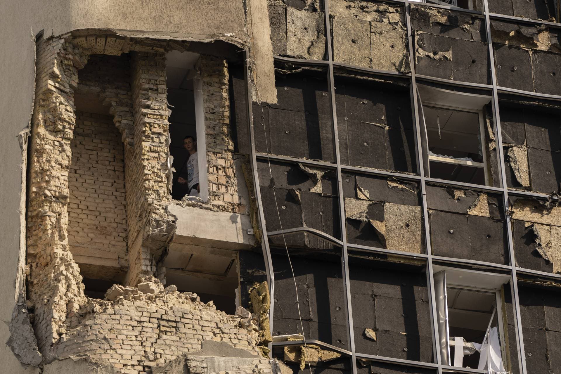 A person looks out the window of a damaged government building in Kyiv