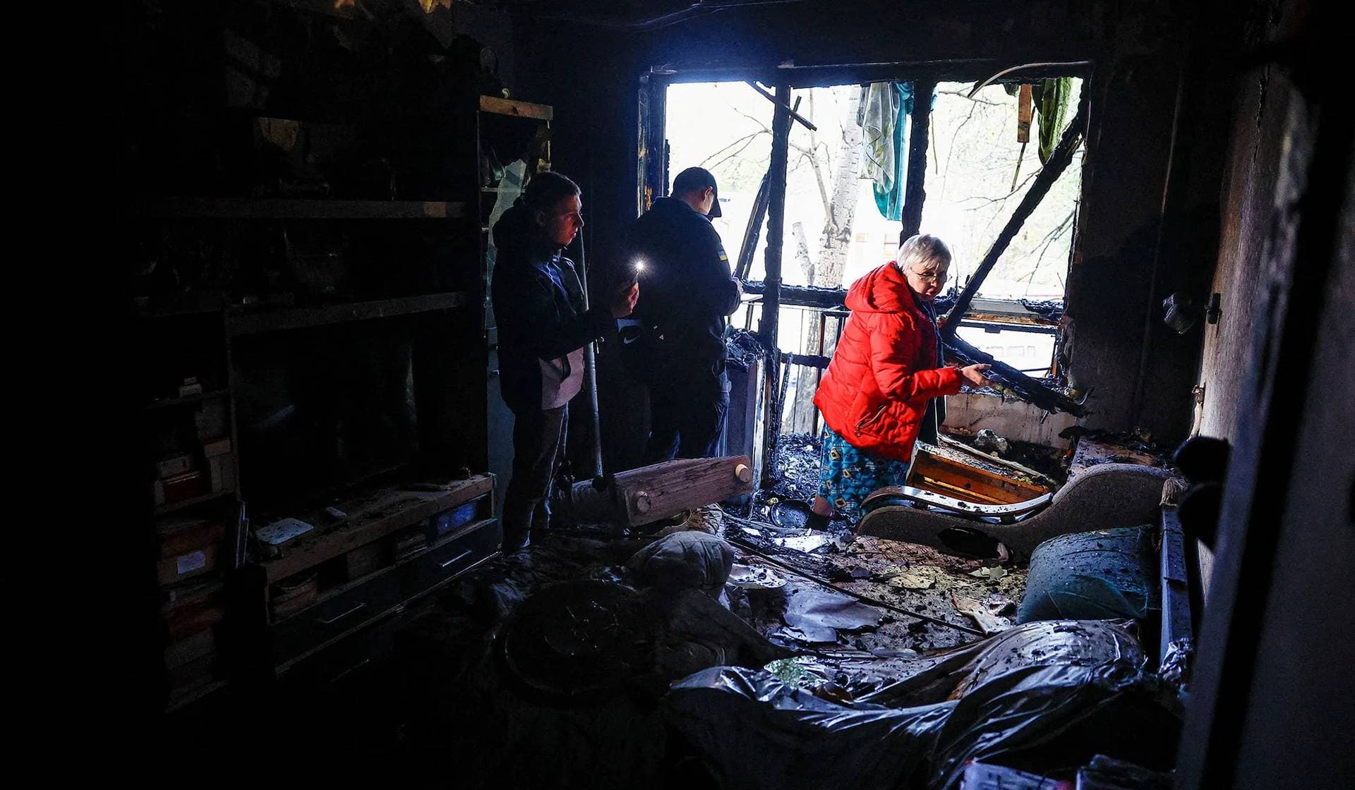 A resident woman shows police officers her apartment, which was damaged by a Russian drone strike in Kyiv