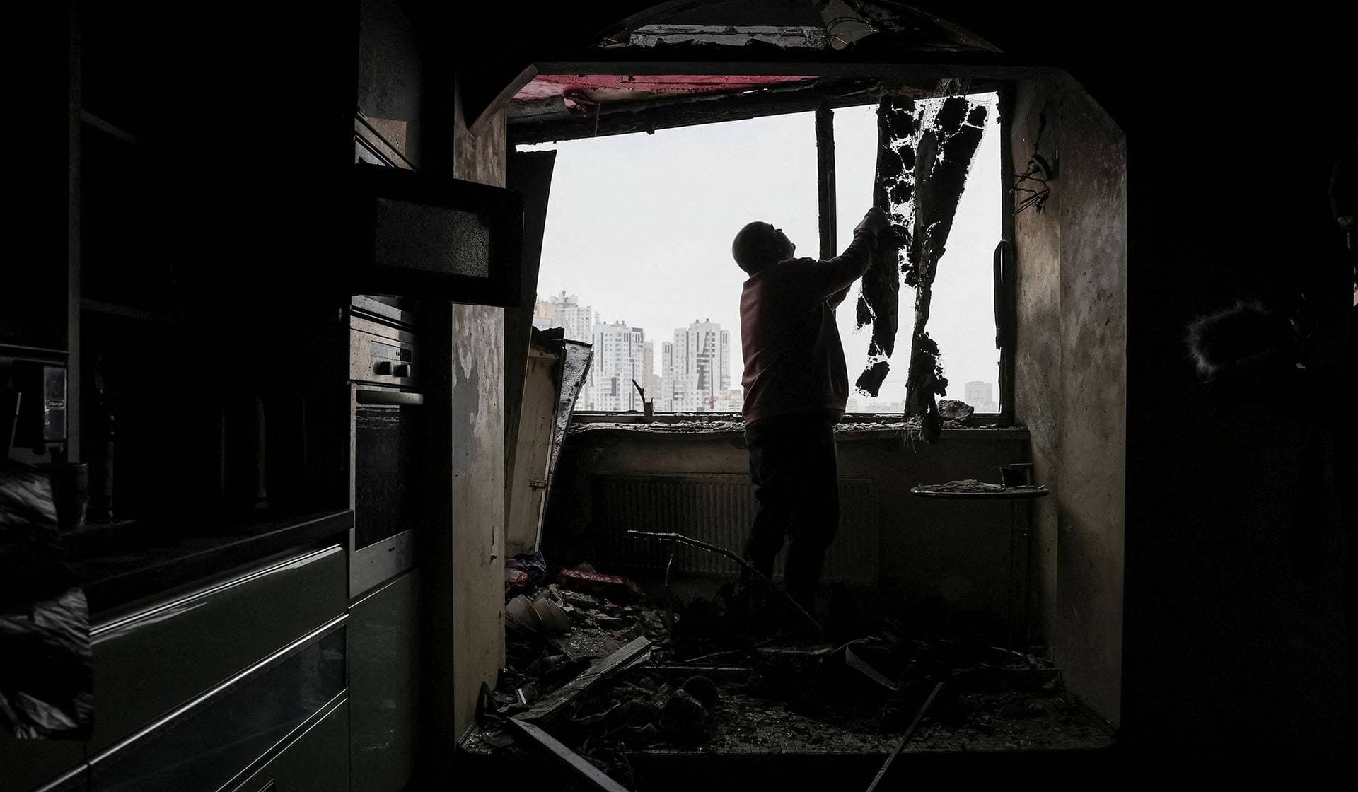 A resident cleans his flat in an apartment building damaged by a Russian drone strike in Kyiv
