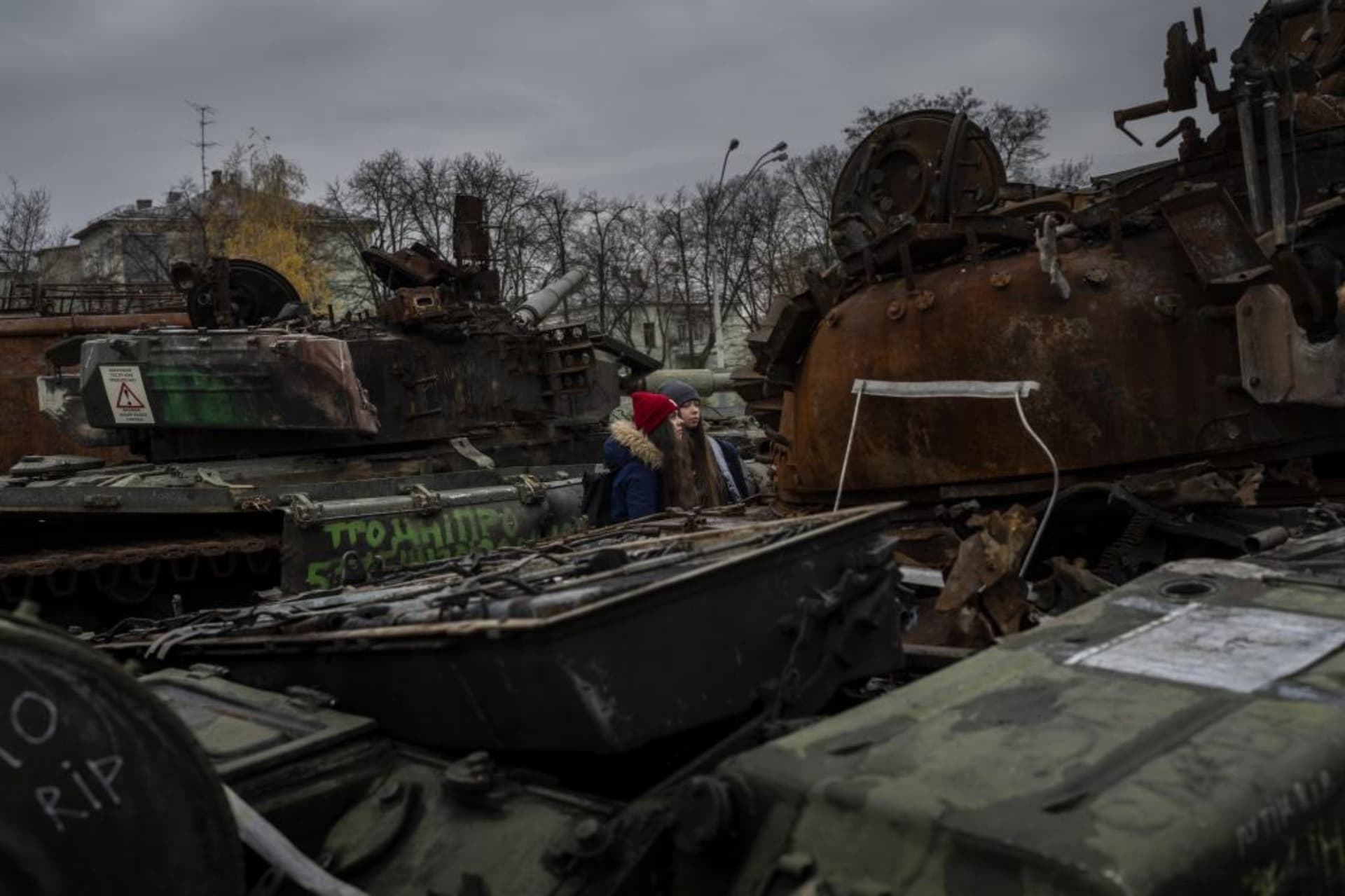 Women stand in front of a display of destroyed Russian tanks and armoured vehicles in downtown Kyiv