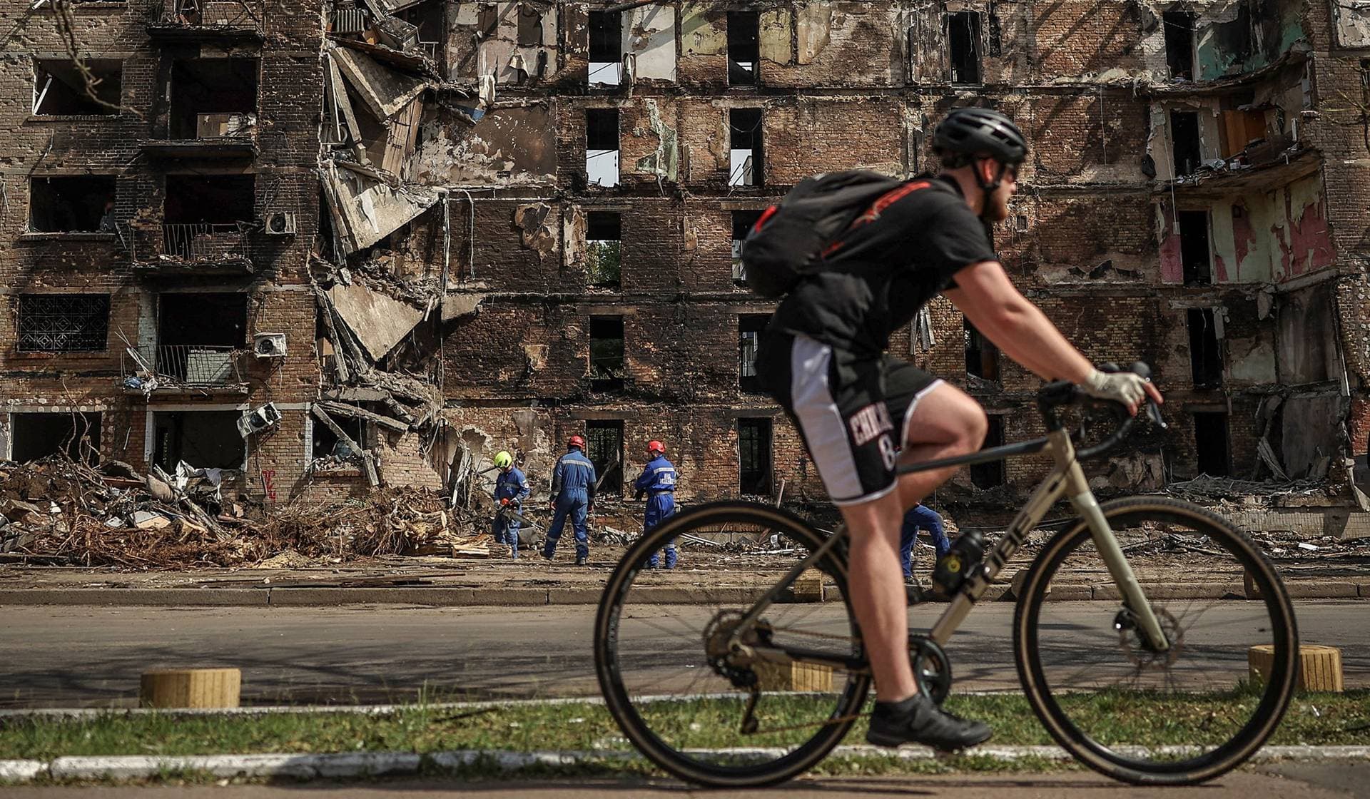 A cyclist rides by a damaged residential building, which was hit during the previous day's Russian missile and drone attack in Kyiv