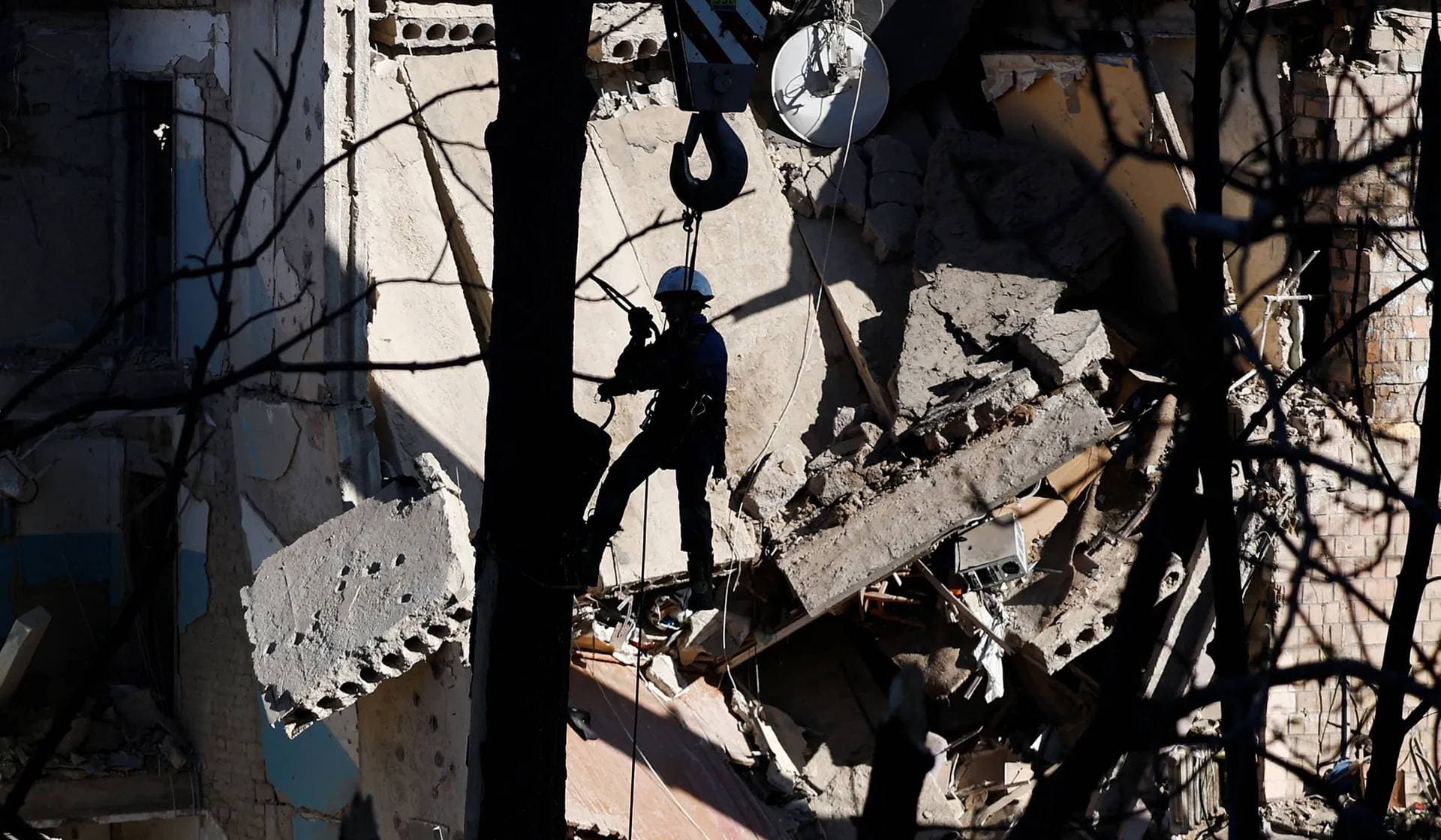 An emergency personnel works in front of a damaged apartment building hit during Russian drone and missile strikes in Kyiv