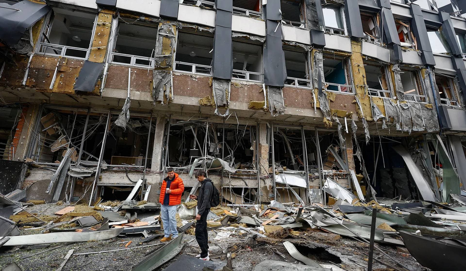 Residents inspect debris in front of a business center damaged during an overnight Russian drone strike in Kyiv
