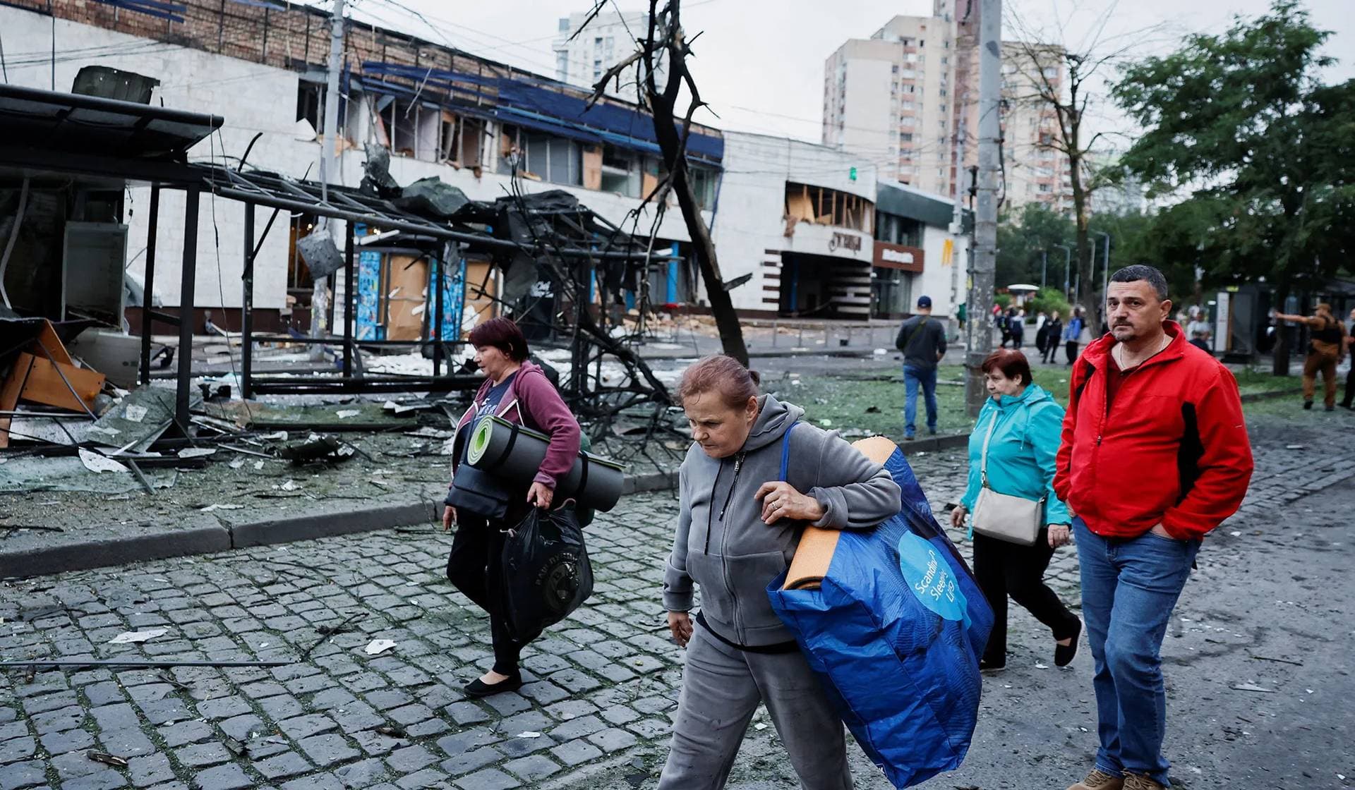 People who sheltered in a metro station during the night of Russian drone and missile strikes, leave the damaged metro station in Kyiv