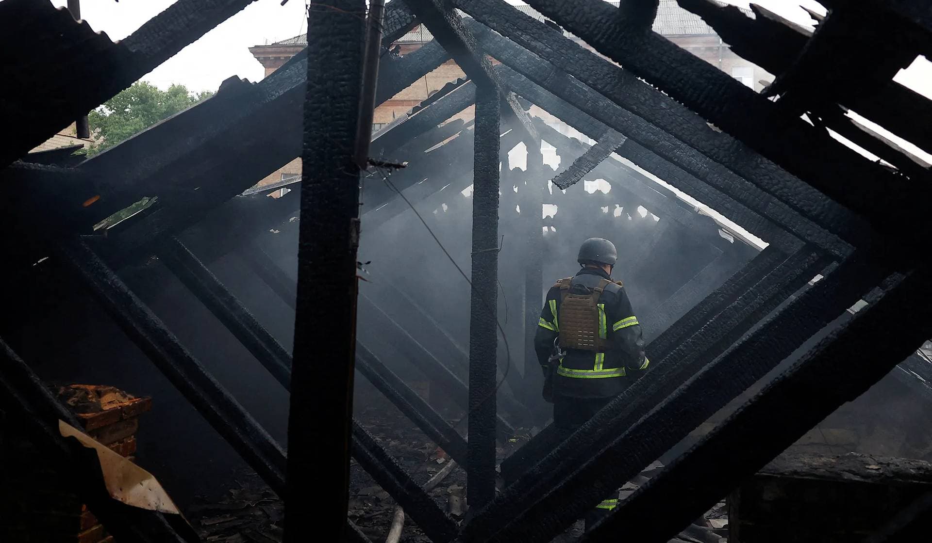 A firefighter stands on a roof of an apartment building, damaged during Russian drone and missile strikes in Kyiv