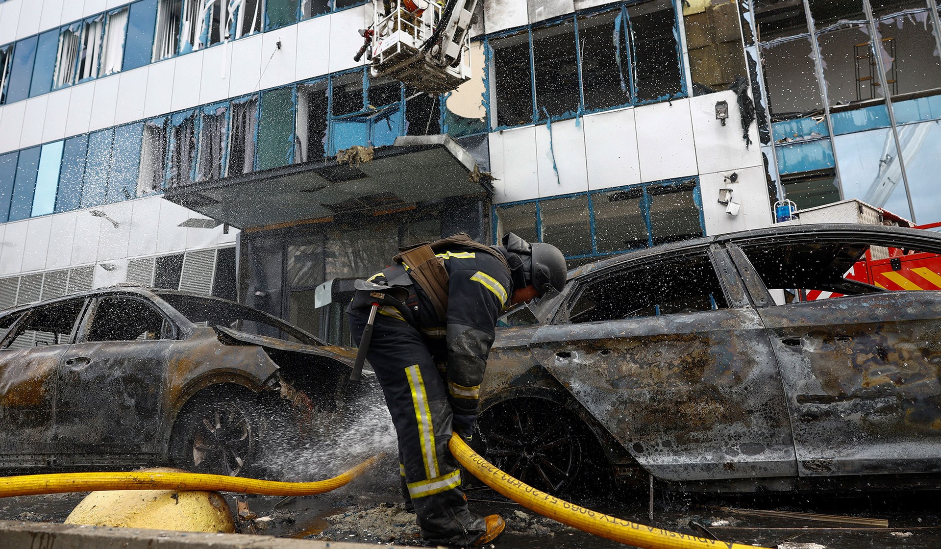 A firefighter works at the site of an office building hit by a Russian drone strike in Kyiv