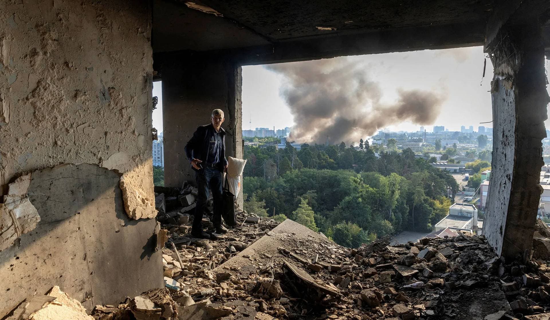 A friend of the owner inspects the damage in an apartment that was hit during a Russian drone strike in Kyiv