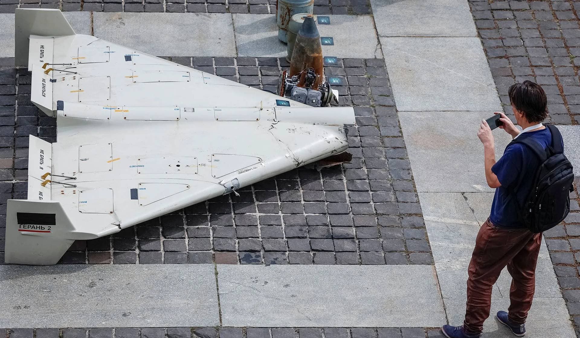 A visitor of an exhibition takes a photo of parts of an Iranian-made Shahed unmanned aerial vehicle which was launched on Ukrainian territories in Kyiv