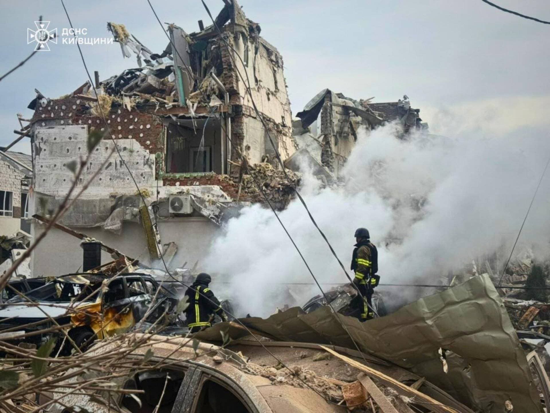 Firefighters work at a residential neighbourhood hit by the Russian drone and missile strike in the outskirts of Kyiv